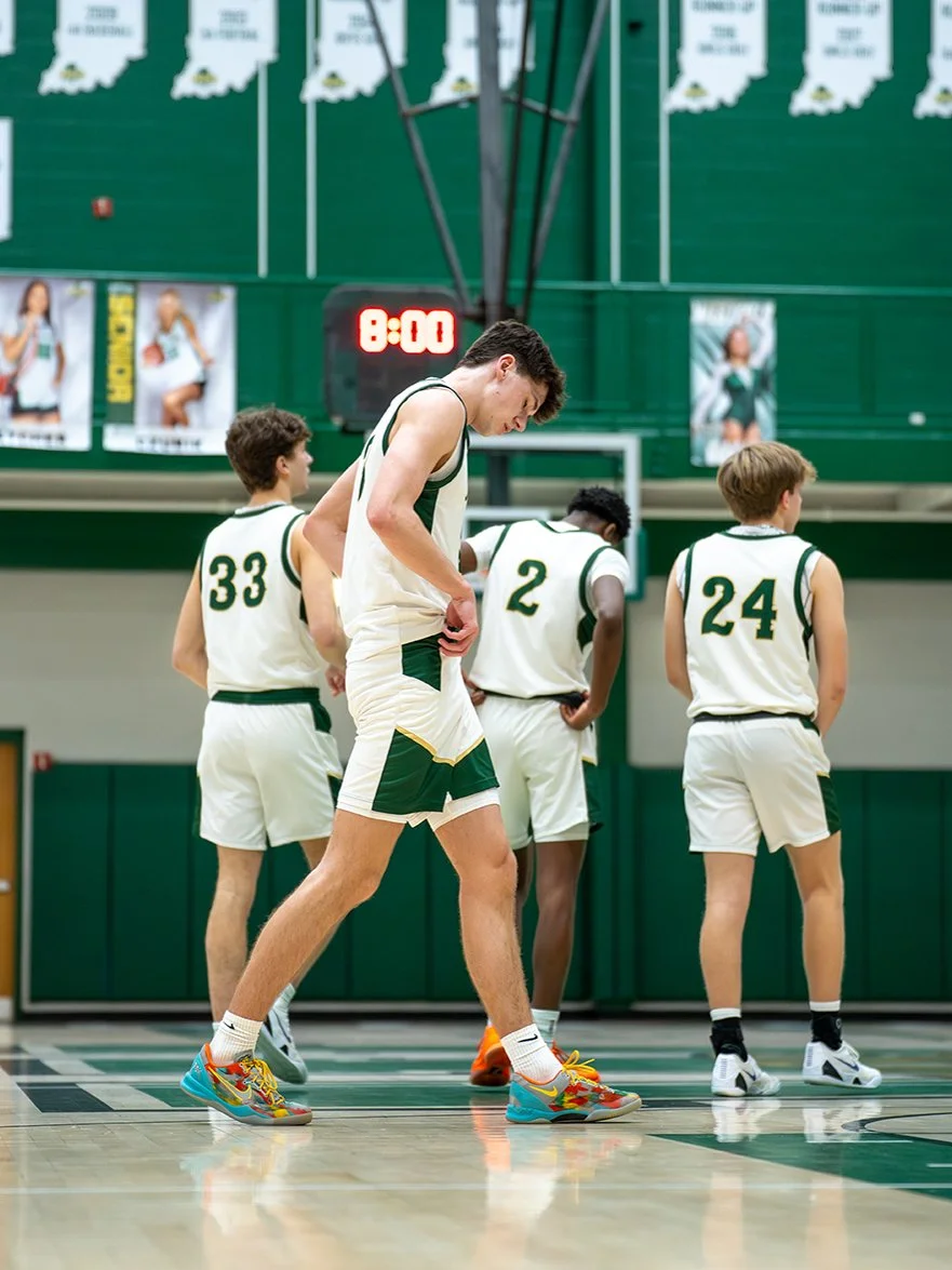 A group of male basketball players in white and green uniforms standing on a basketball court with a digital scoreboard displaying 8:00 in the background.