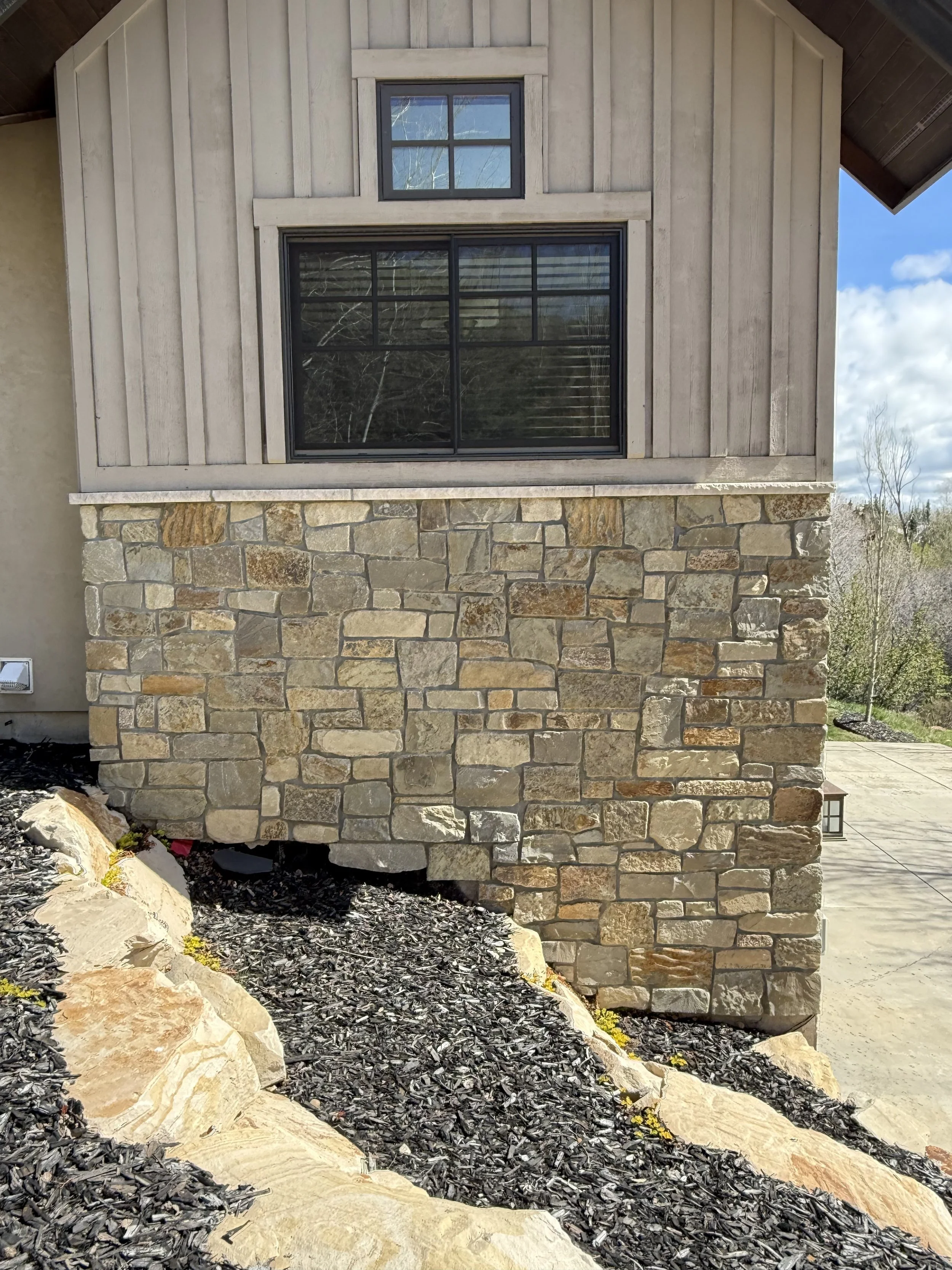 Custom restoration in San Diego featuring masonry work to repair stone veneer on side of house.