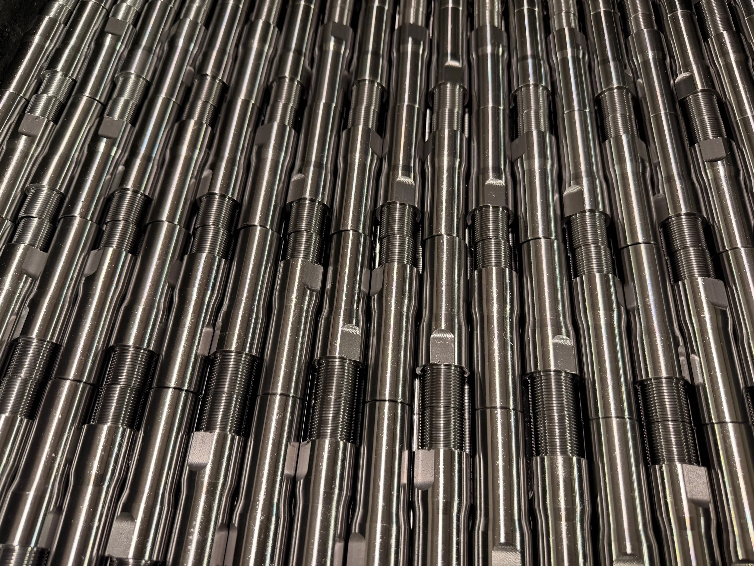 Multiple metal rods or bolts arranged parallel, with threaded ends and hexagonal nuts.