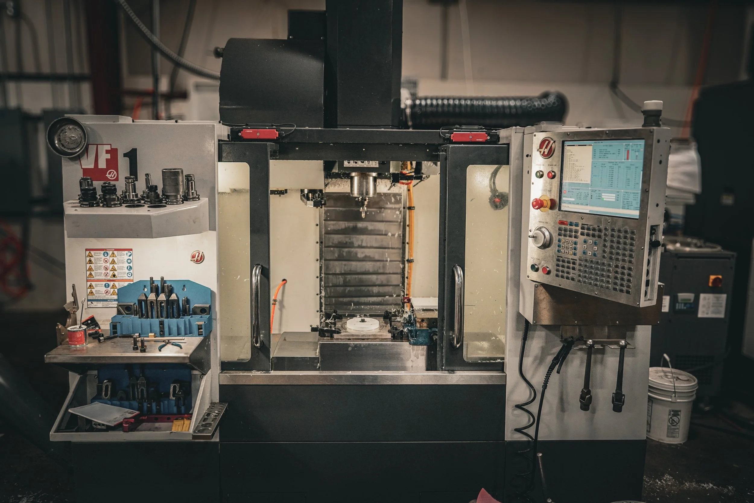 Industrial CNC machine in a workshop with tools and computer control panel.