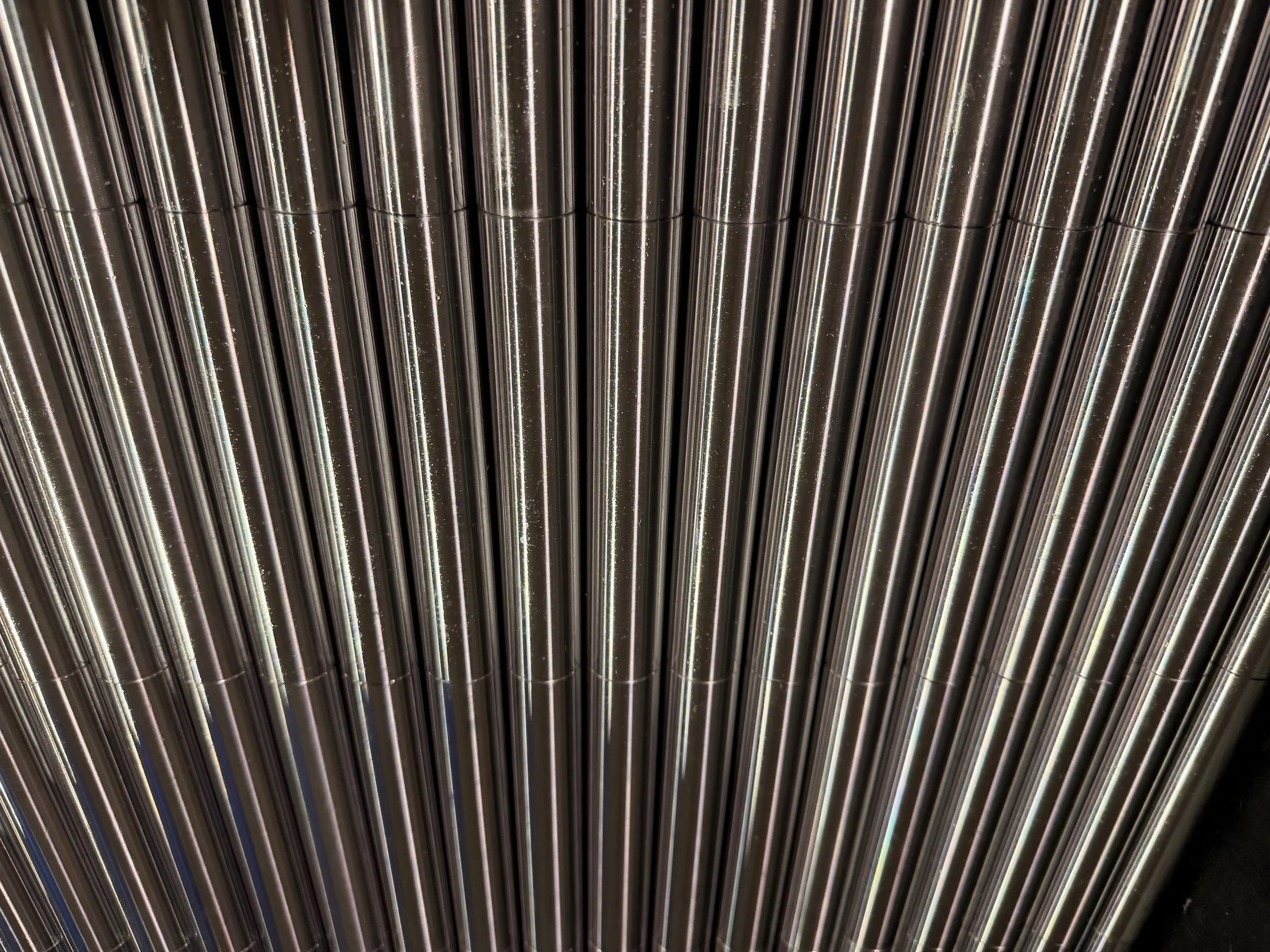 Close-up view of metallic pipes or tubes arranged vertically.