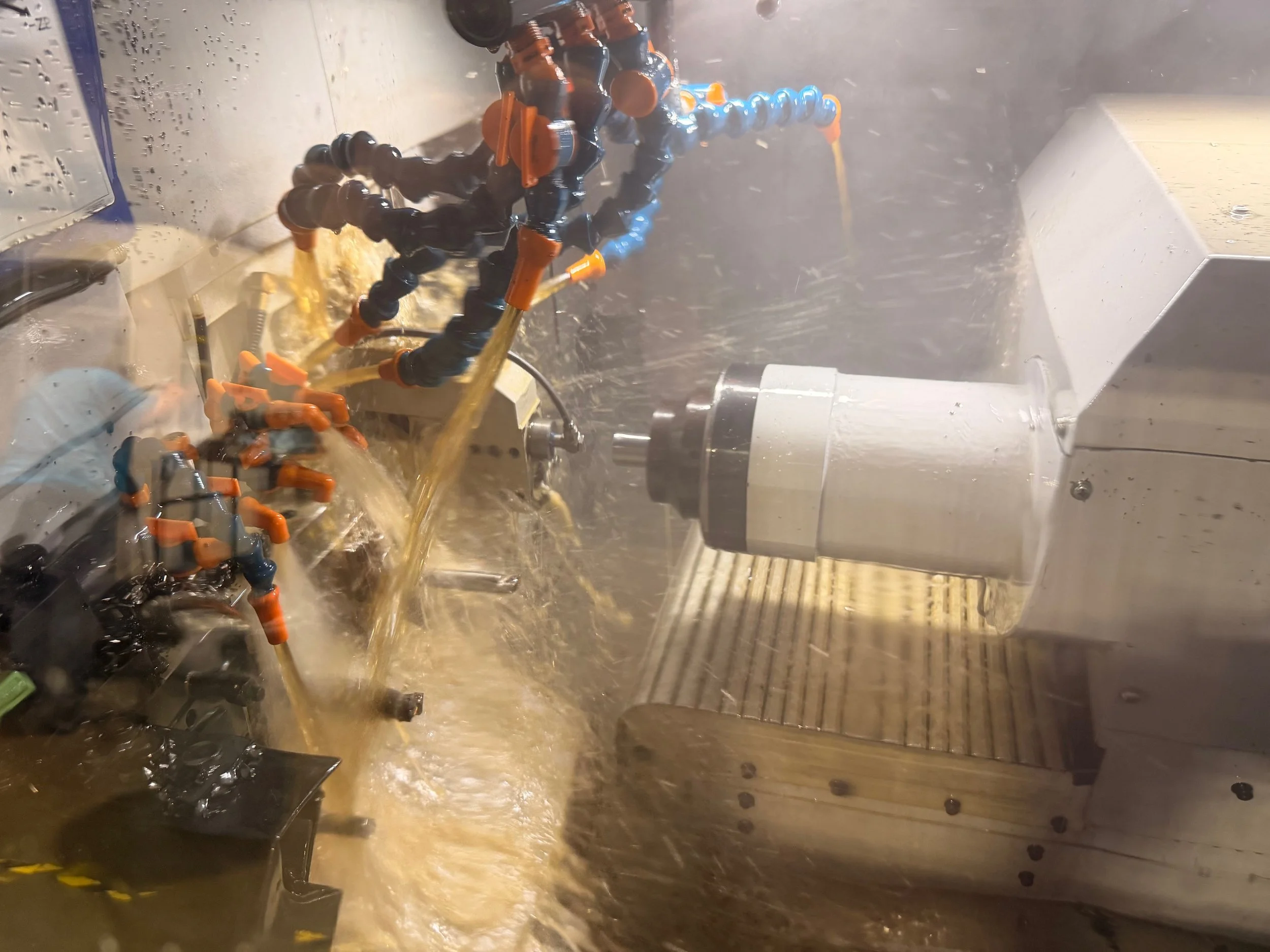 A CNC machine with coolant spray while machining metal parts.