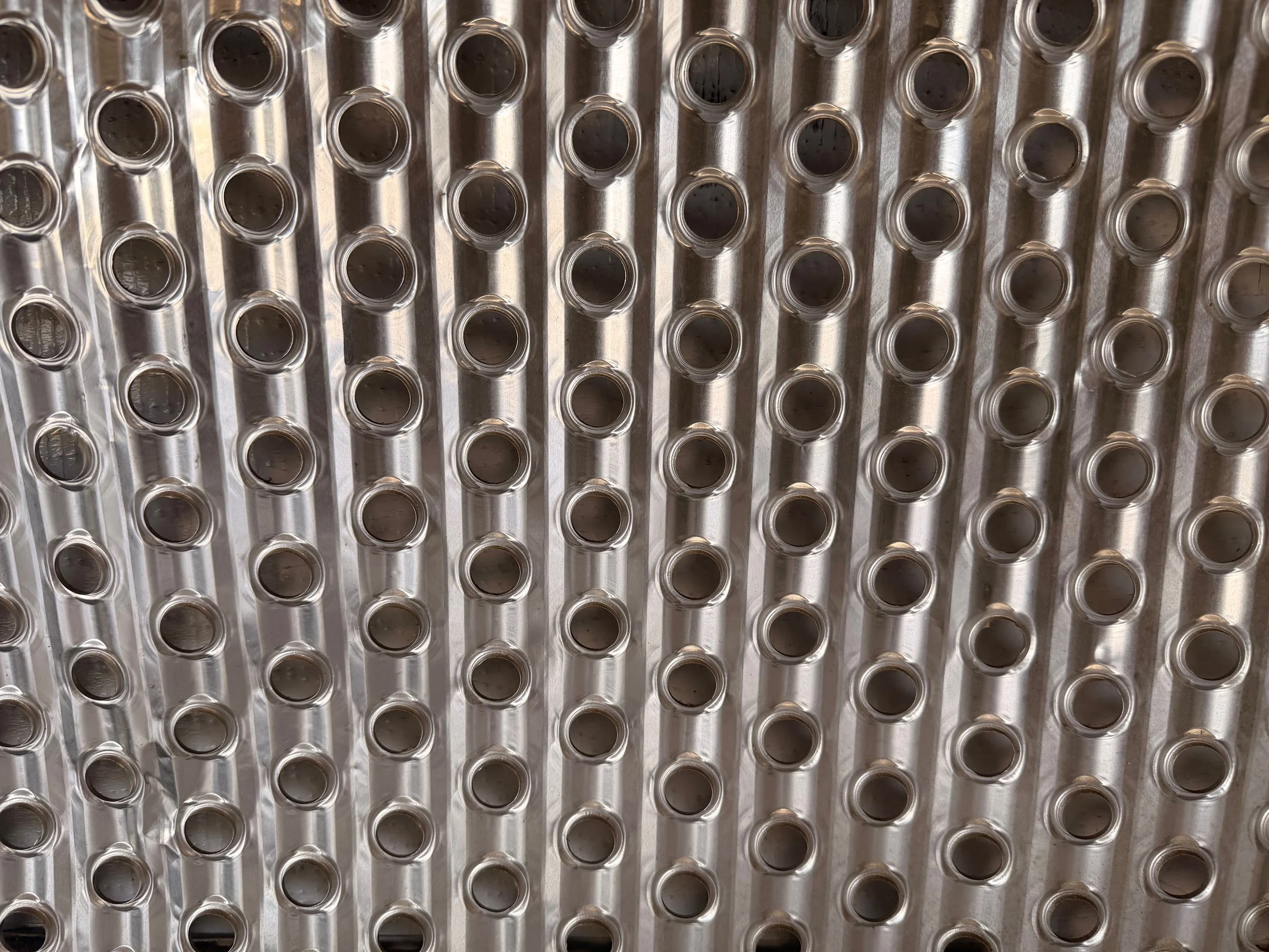 Close-up view of a metallic heat exchanger or cooling coil with multiple tubes arranged in vertical rows.