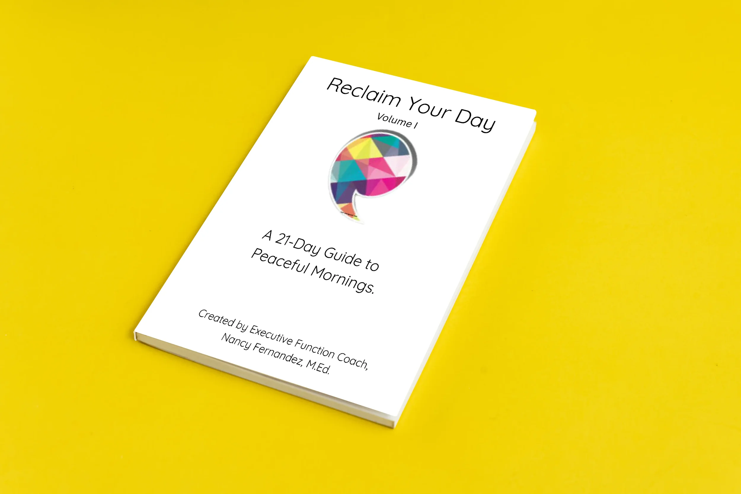 A white book titled "Reclaim Your Day, Volume 1," resting on a bright yellow surface. The cover features a colorful, geometric chat bubble logo and a subtitle about a 21-day guide to peaceful mornings. The author's name, Nancy Fernandez, M. Ed., appears at the bottom.