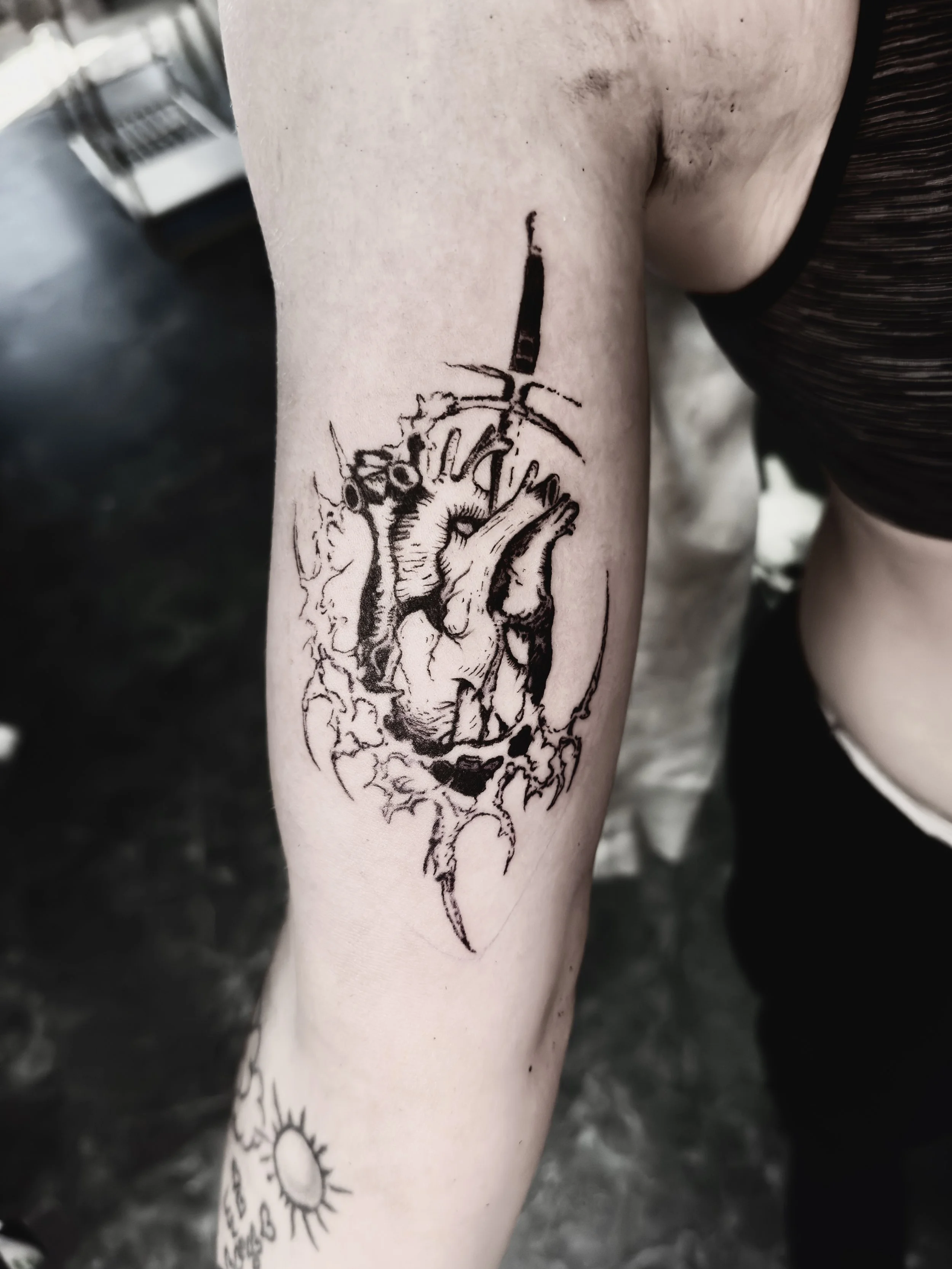 Tattoo of a detailed anatomical heart with a dagger piercing through it on a person's forearm.