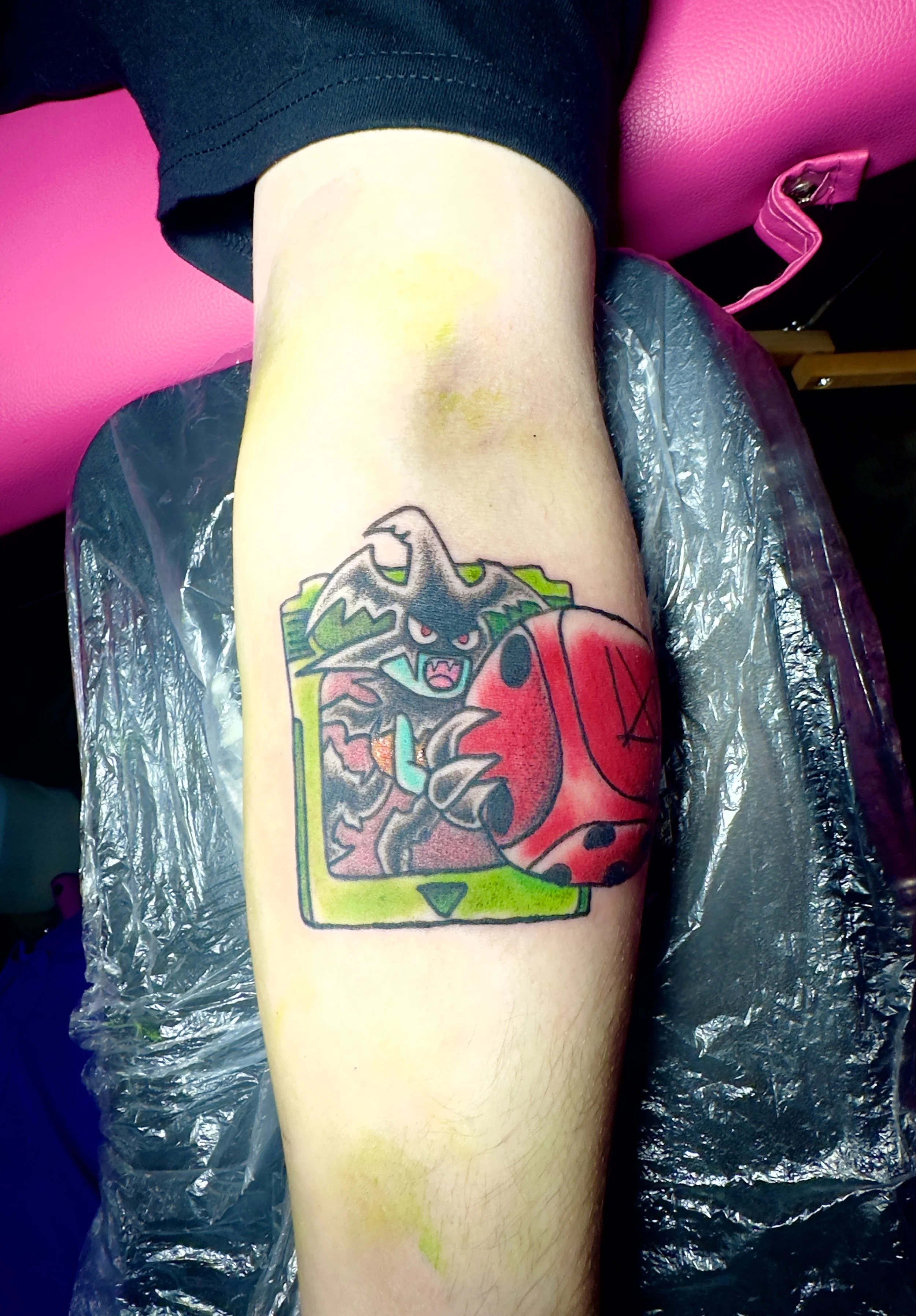 Tattoo of a dark wolf-like creature with red eyes and sharp teeth holding a red ladybug, inside a green-bordered rectangle. Skull Dice from Yu-Gi-Oh!