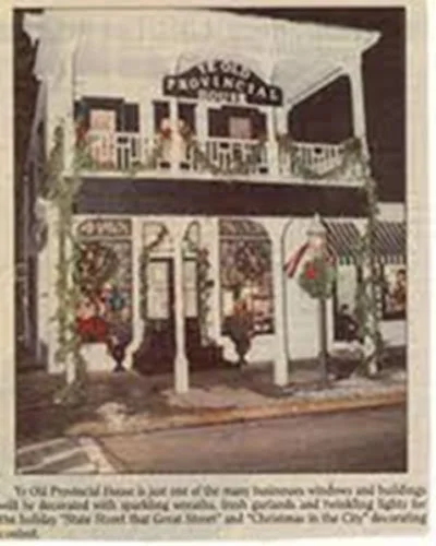 Two-story building with a sign reading "The Knowledge" on the upper level, decorated with hanging flower baskets and outdoor seating.