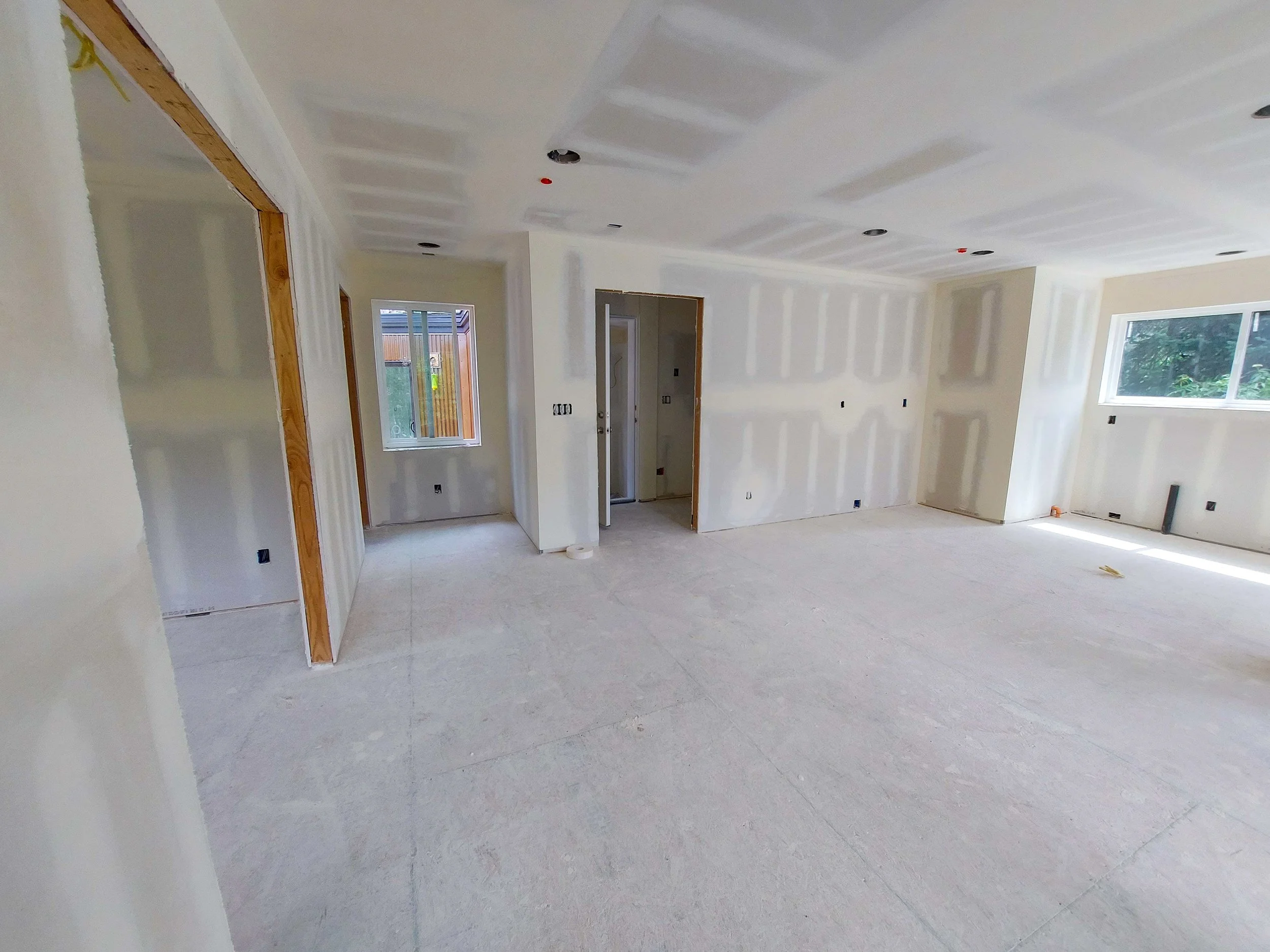 Interior of a house under construction with unfinished drywall walls and ceiling, ready for primer and paint