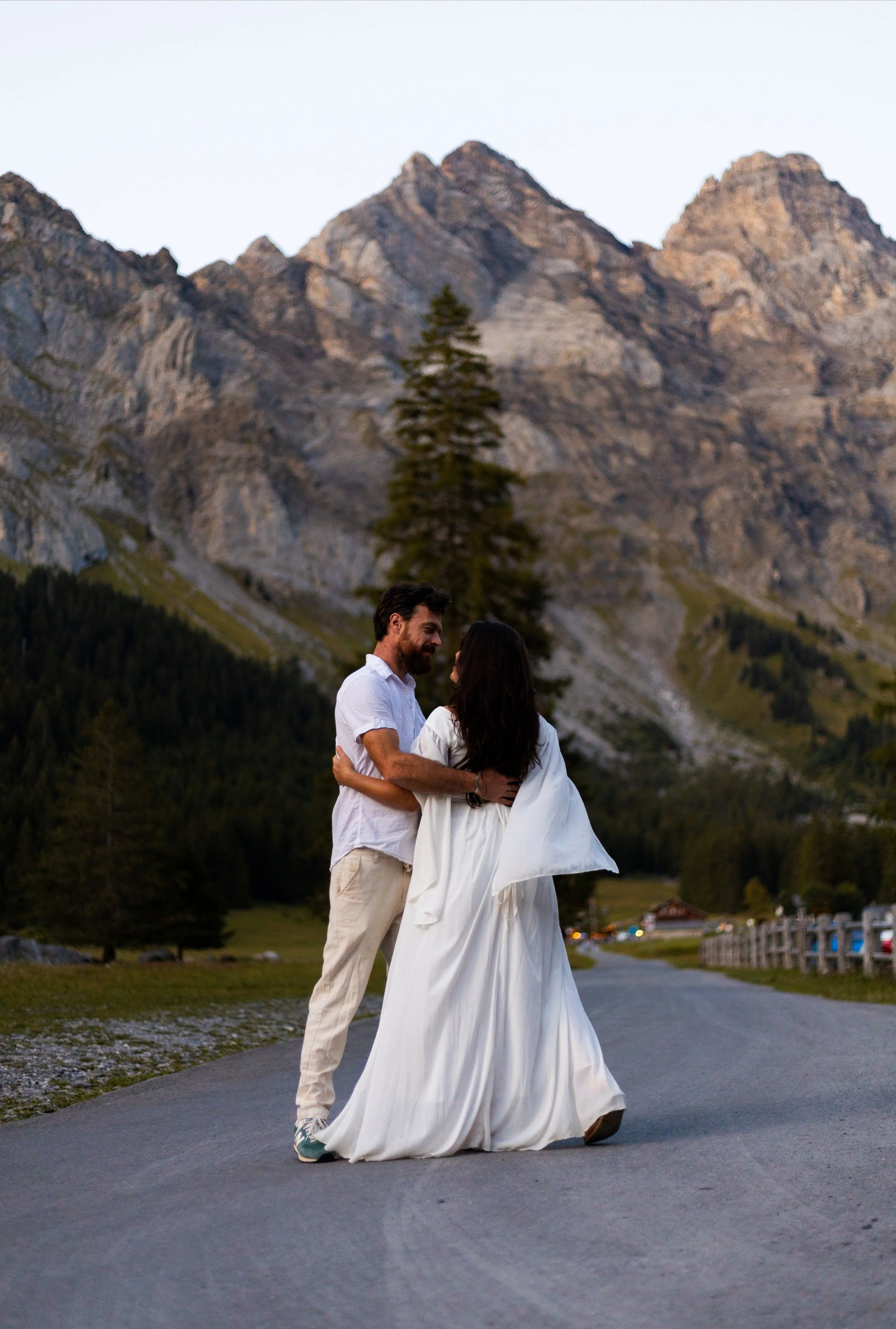 Un couple danse dans une vallée de montagne avec un canyon rocheux en arrière-plan, au crépuscule.