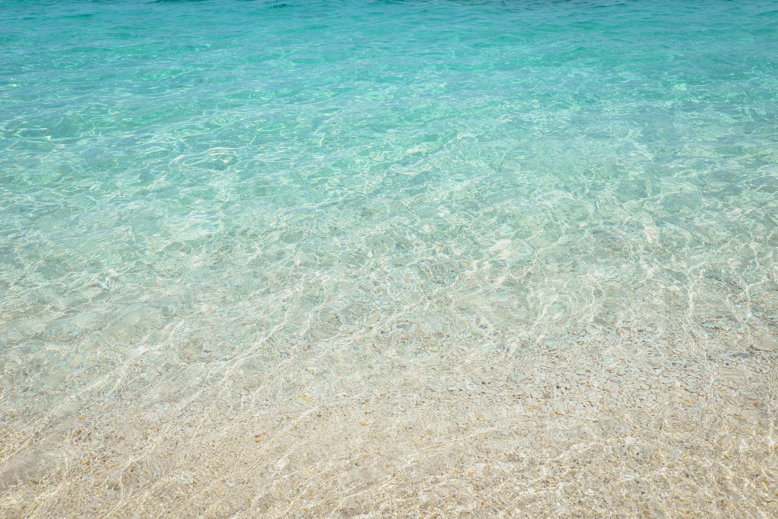 Clear turquoise water at the beach with visible sandy bottom. Meaning behind is that everything is energy and connected; water with it's ripple effect.