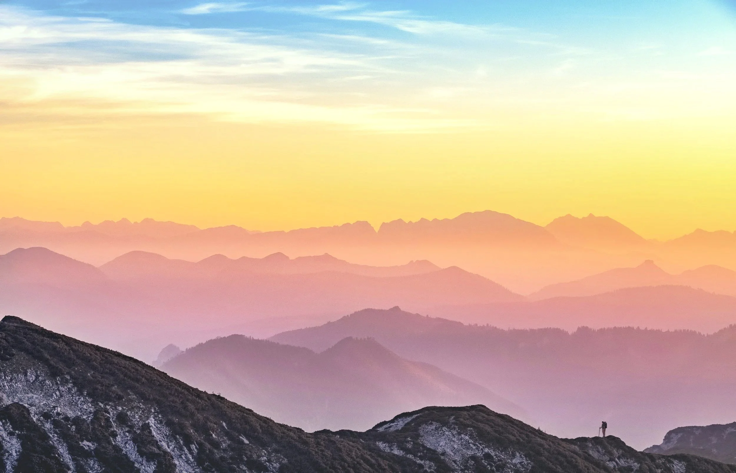 Landscape of mountain range during sunset with colorful sky and layers of mountains fading into the distance. Meaning behind is that Light reveals, holds attention and truth.