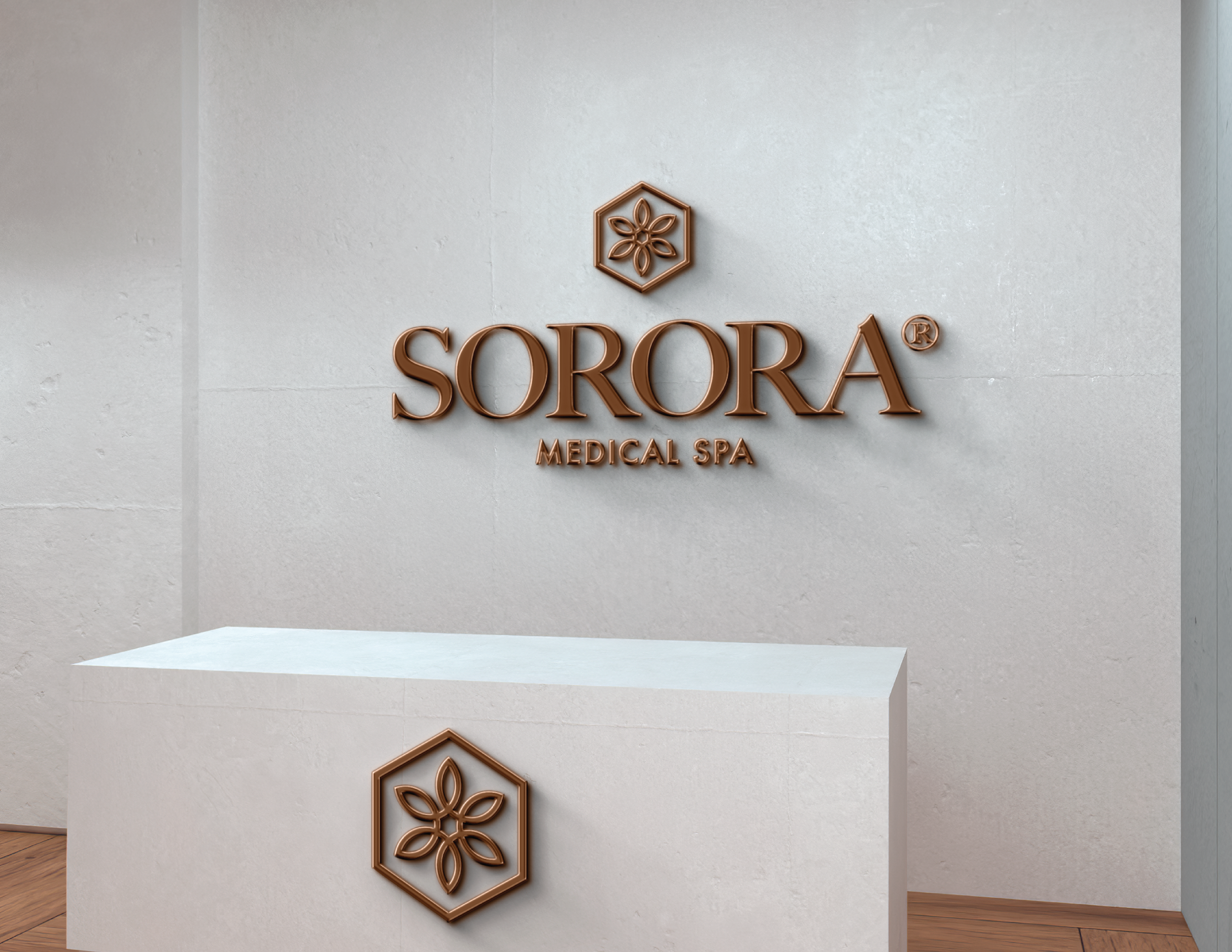 Reception desk in a medical spa with a sign on the wall that reads 'SORORA Medical Spa' and a logo featuring a flower within a hexagon.