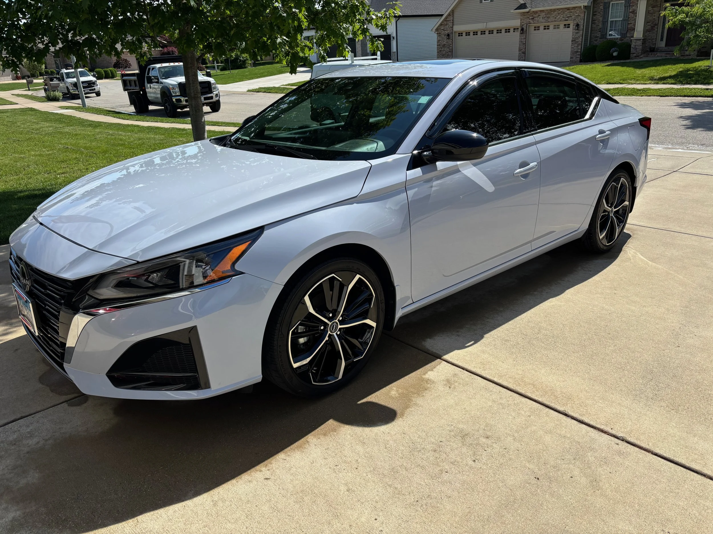 Glossy exterior hand wash and tire dressing on white Nissan sedan in Springfield IL driveway