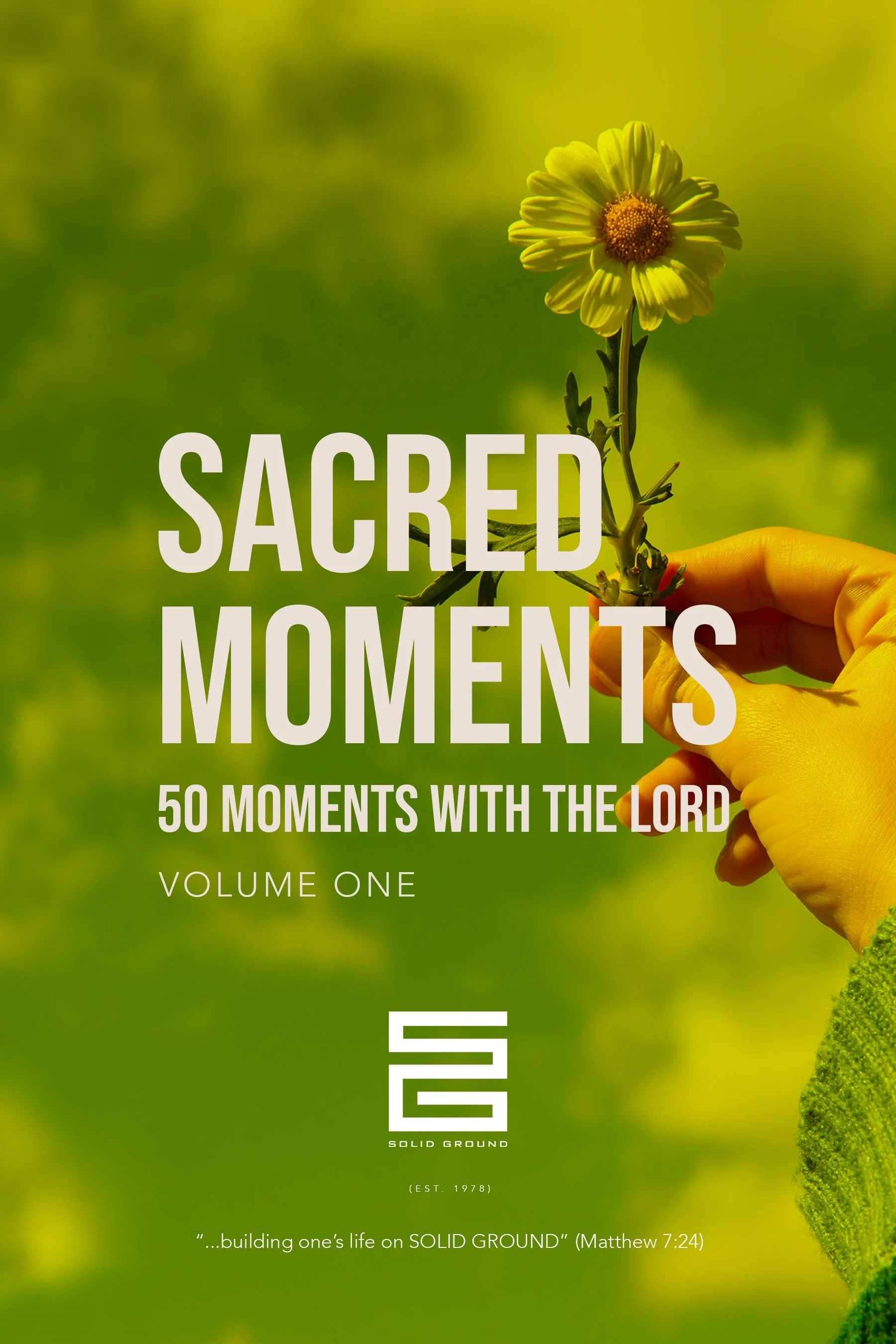 A hand wearing a yellow glove holding a stem with a yellow flower against a blurred green background, with the overlay text "Sacred Moments" and other text about a book or journal titled "Solid Ground".