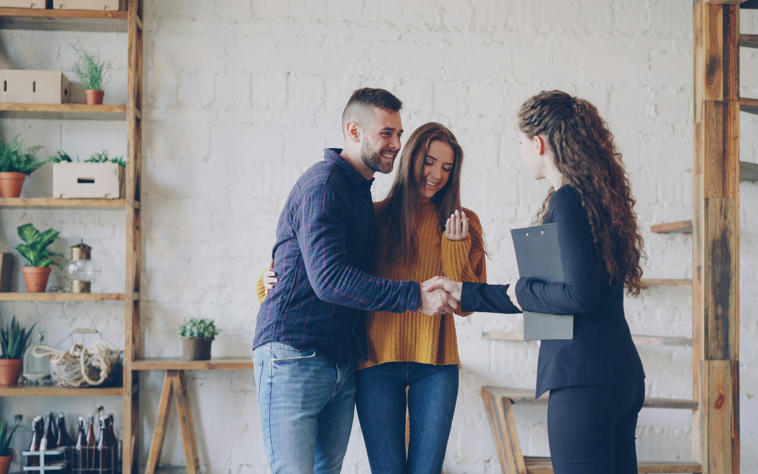 Couple shaking hands with service business owner.