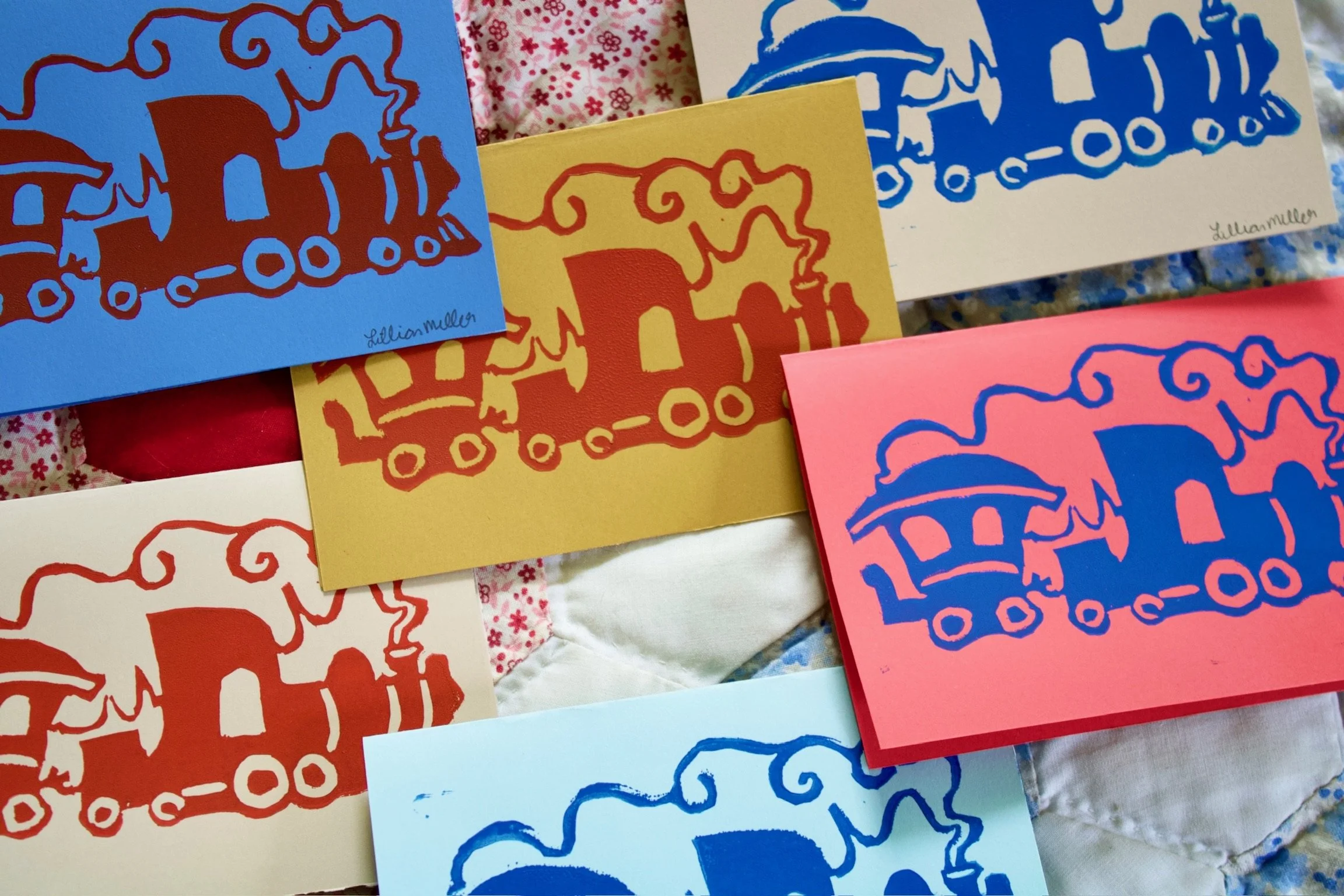 Colorful illustrations of elephants on various colored paper sheets, with some floral fabric visible in the background.