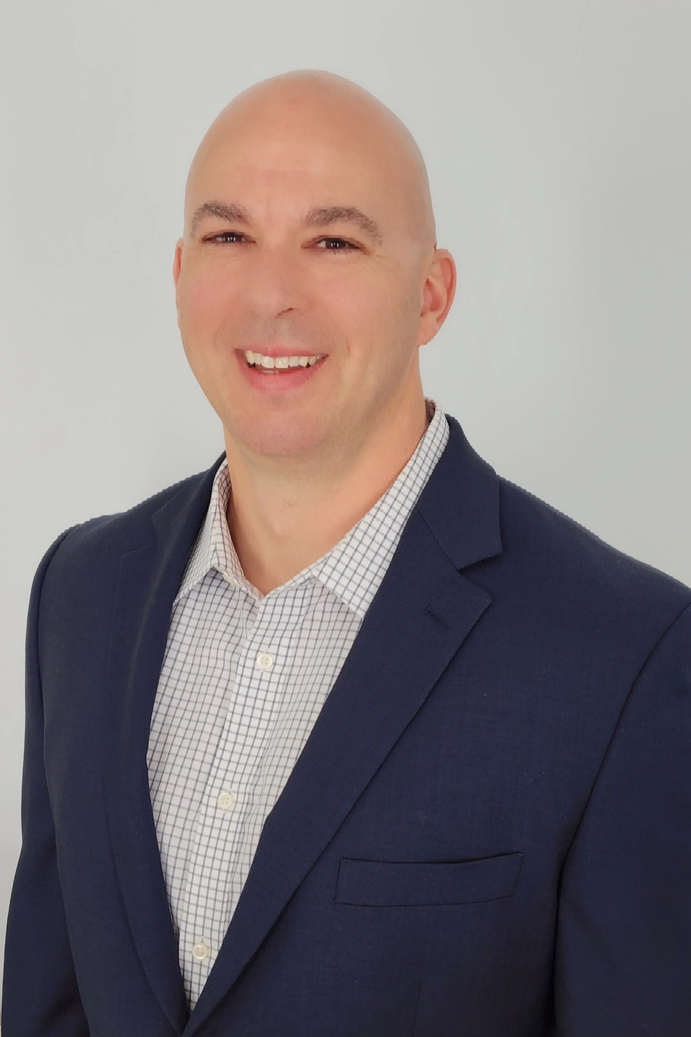 Vanguard 1 Leadership - Jerry Cook wearing a checkered dress shirt and a dark blazer, smiling against a plain white background.