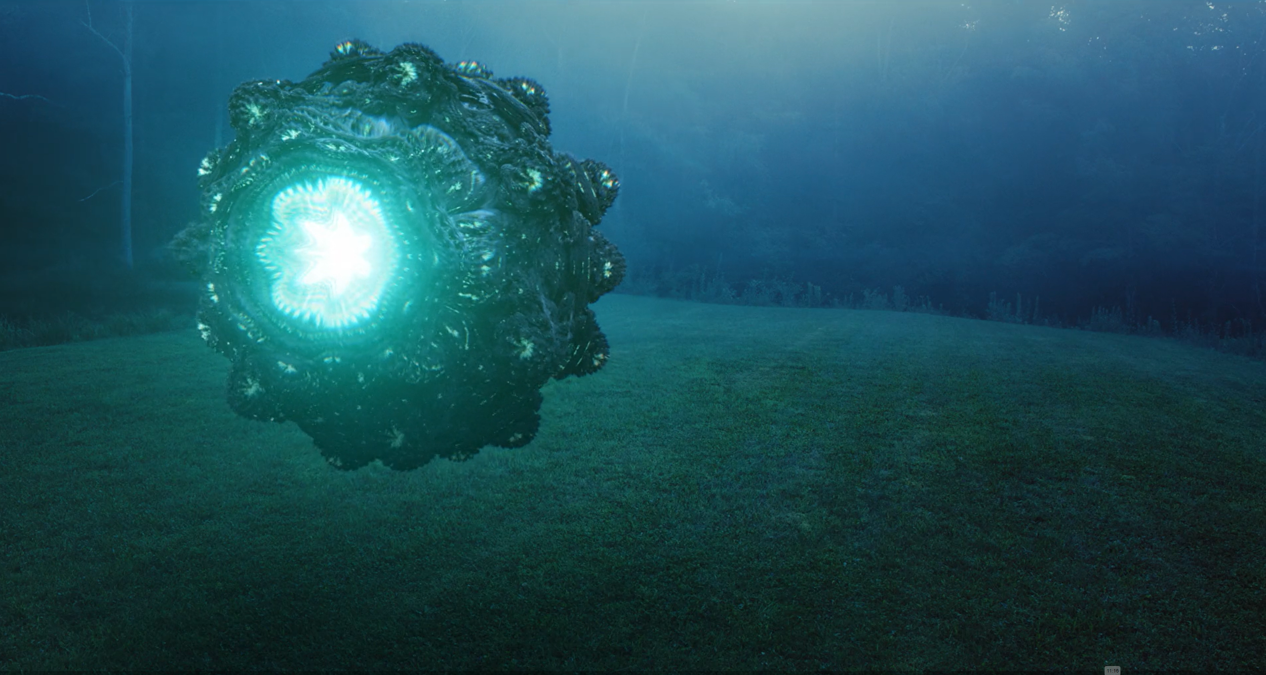 A large, dark, amorphous alien creature with a glowing blue light at its center, floating above a grassy field at dusk or dawn, with a mysterious and sci-fi atmosphere.