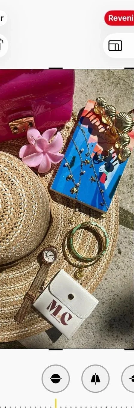 Une collection d'objets de plage et accessoires, incluant un chapeau en paille, des bijoux, des cheveux en plastique, un sac rose, et une montre, tous disposés sur une surface.