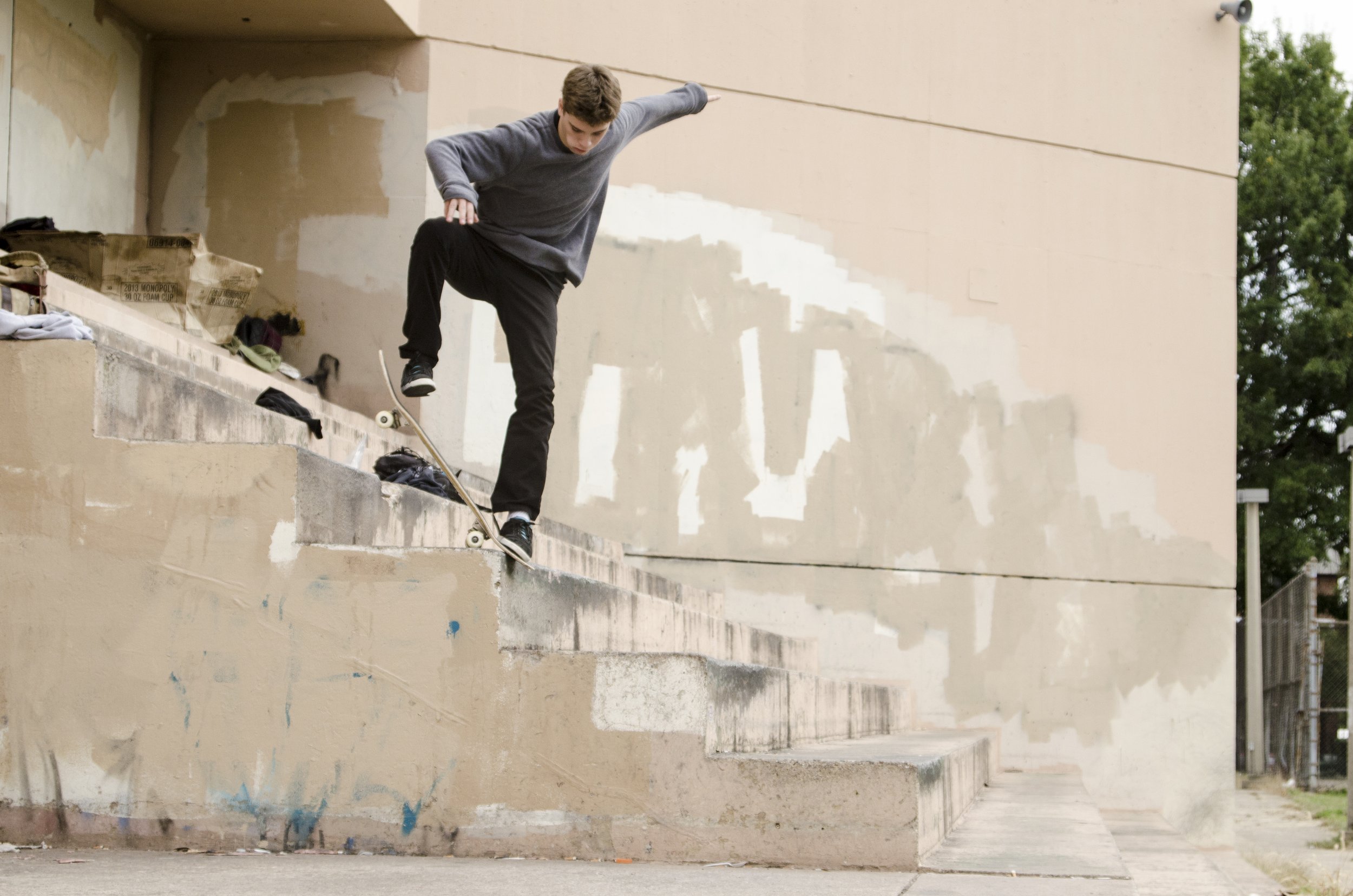 A young male skateboarder performing a trick on a city sidewalk staircase.