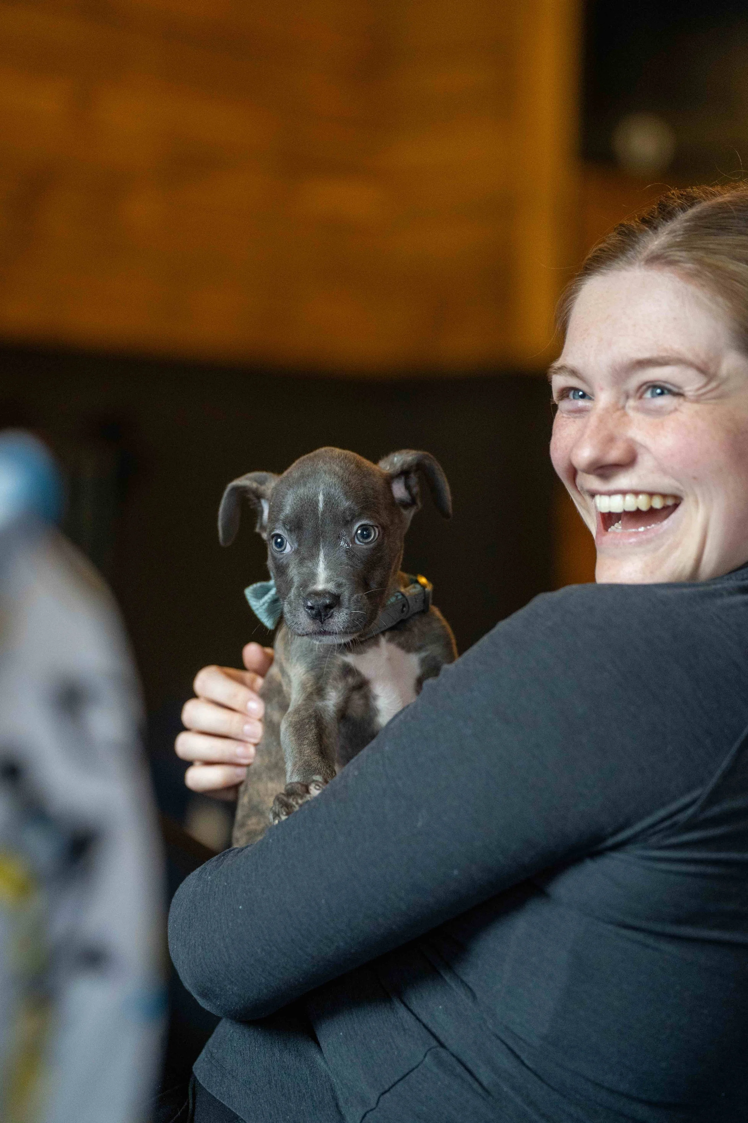 Woman laughing and holding a small puppy