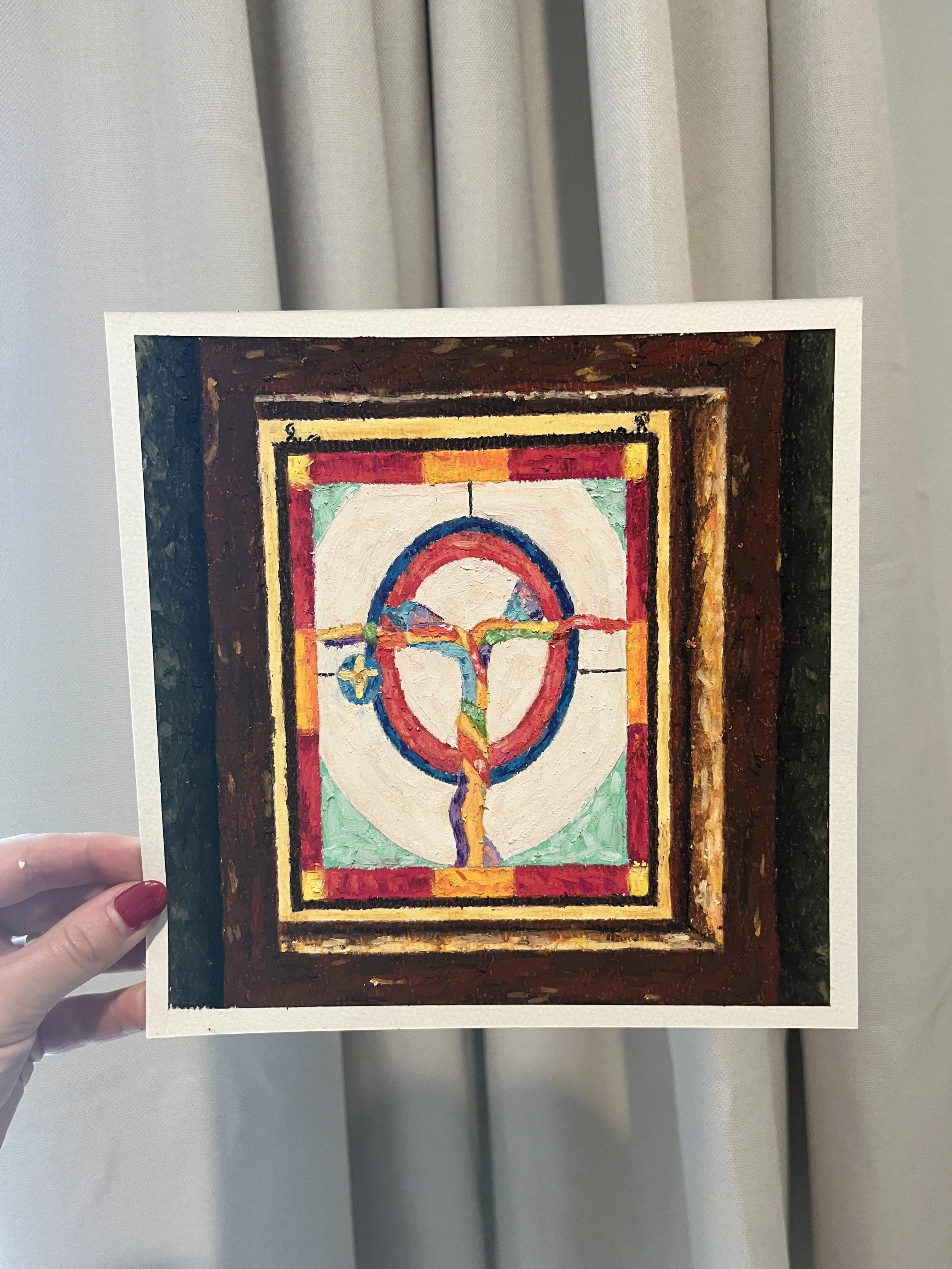 A hand with red nail polish holding a printed picture of a colorful abstract painting, with a white border around it, against a backdrop of light-colored curtains.