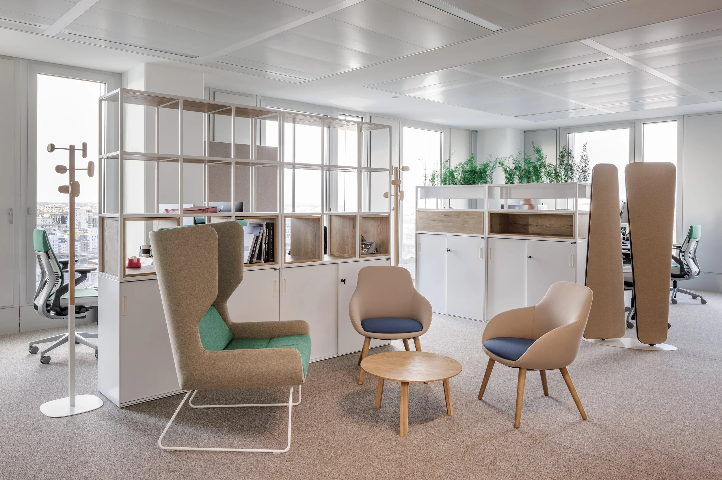 Un bureau moderne avec des chaises confortables, des étagères en bois et de grandes fenêtres laissant entrer la lumière naturelle, en milieu urbain.