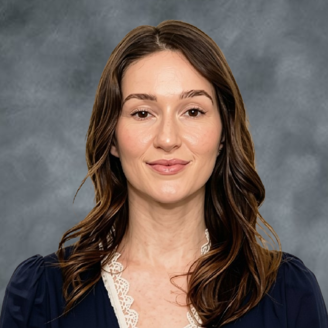 A woman with long brown hair wearing a dark blue top with lace trim, smiling softly against a gray background.