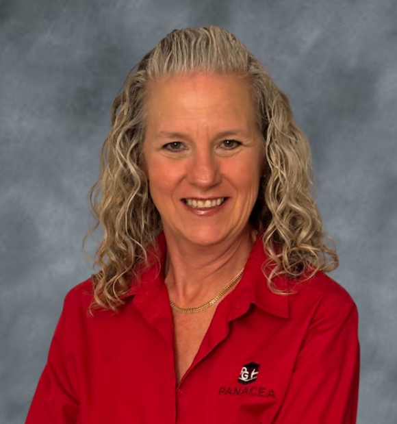 A woman with blonde, curly hair, wearing a red collared shirt with a logo and the text 'PANACEA'. She is smiling.