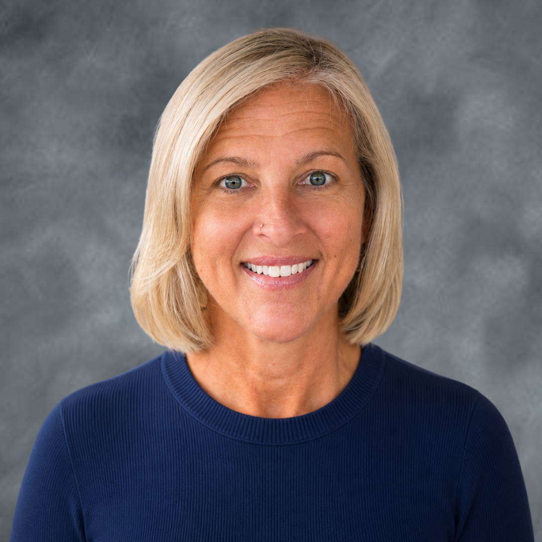 A woman with blonde hair smiling, wearing a navy blue top, against a gray textured background.