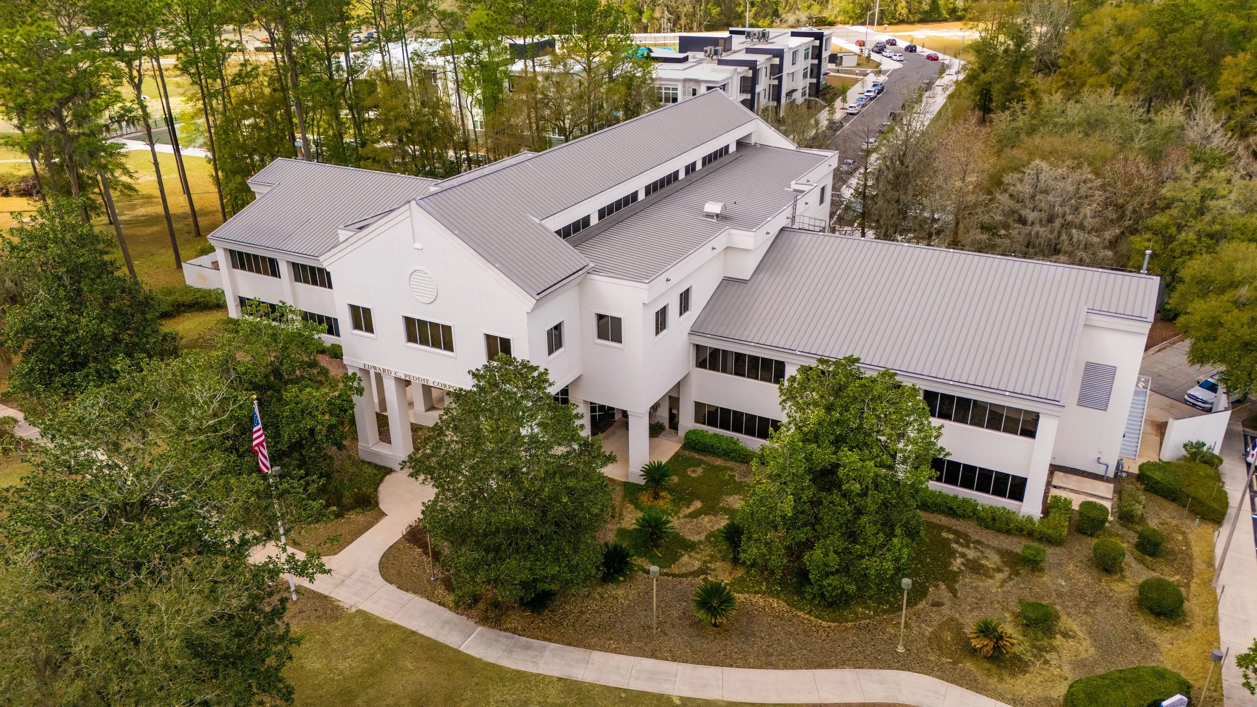 Aerial view of Edward C Peddie Corporate Center, surrounded by trees, with parking lots and other buildings nearby.