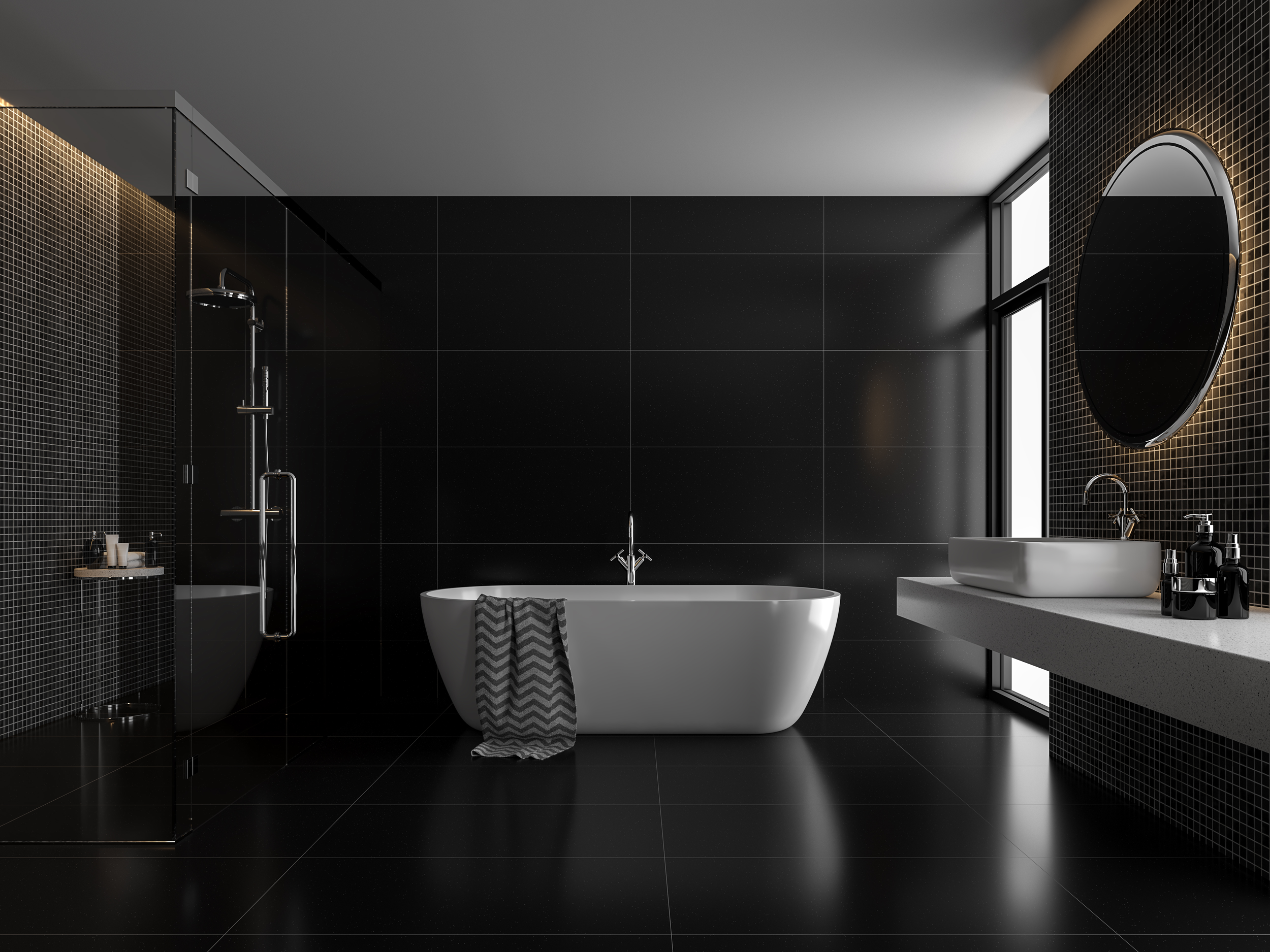 Modern black-tiled bathroom with a black bathtub, a walk-in shower with glass door, a white countertop with vessel sink, a round mirror, and a large window.