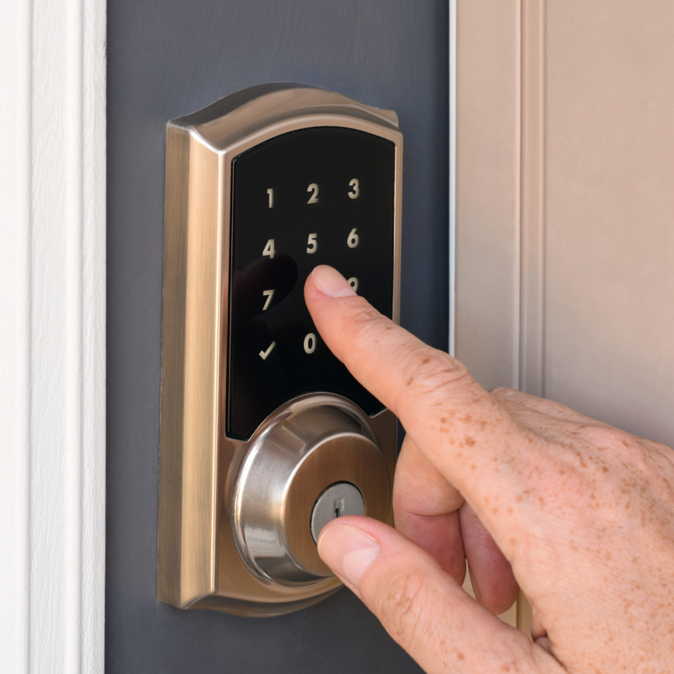 A person pressing a keypad on a door lock system with a keypad and a round keyhole below.
