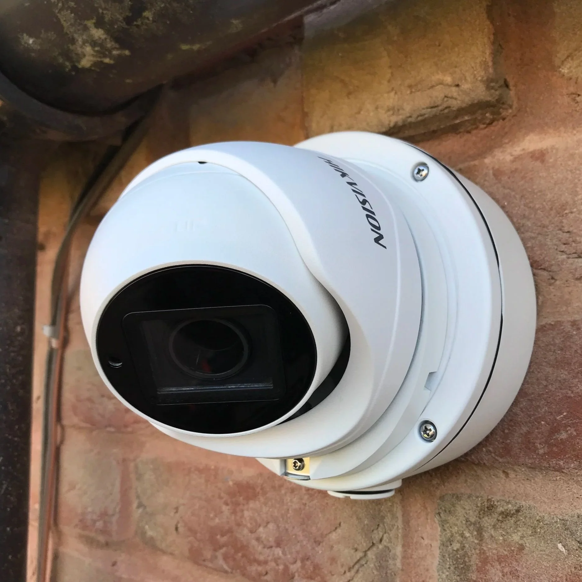 White security camera mounted on a brick wall.