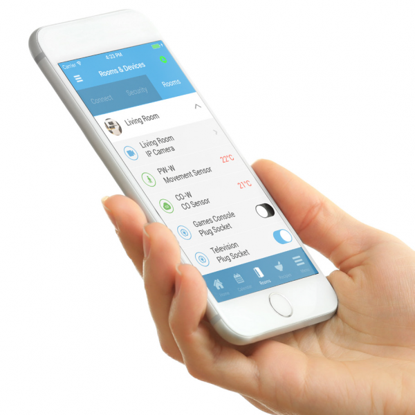 Close-up of a hand holding a smartphone displaying a home automation app with controls for room temperature and smart devices.