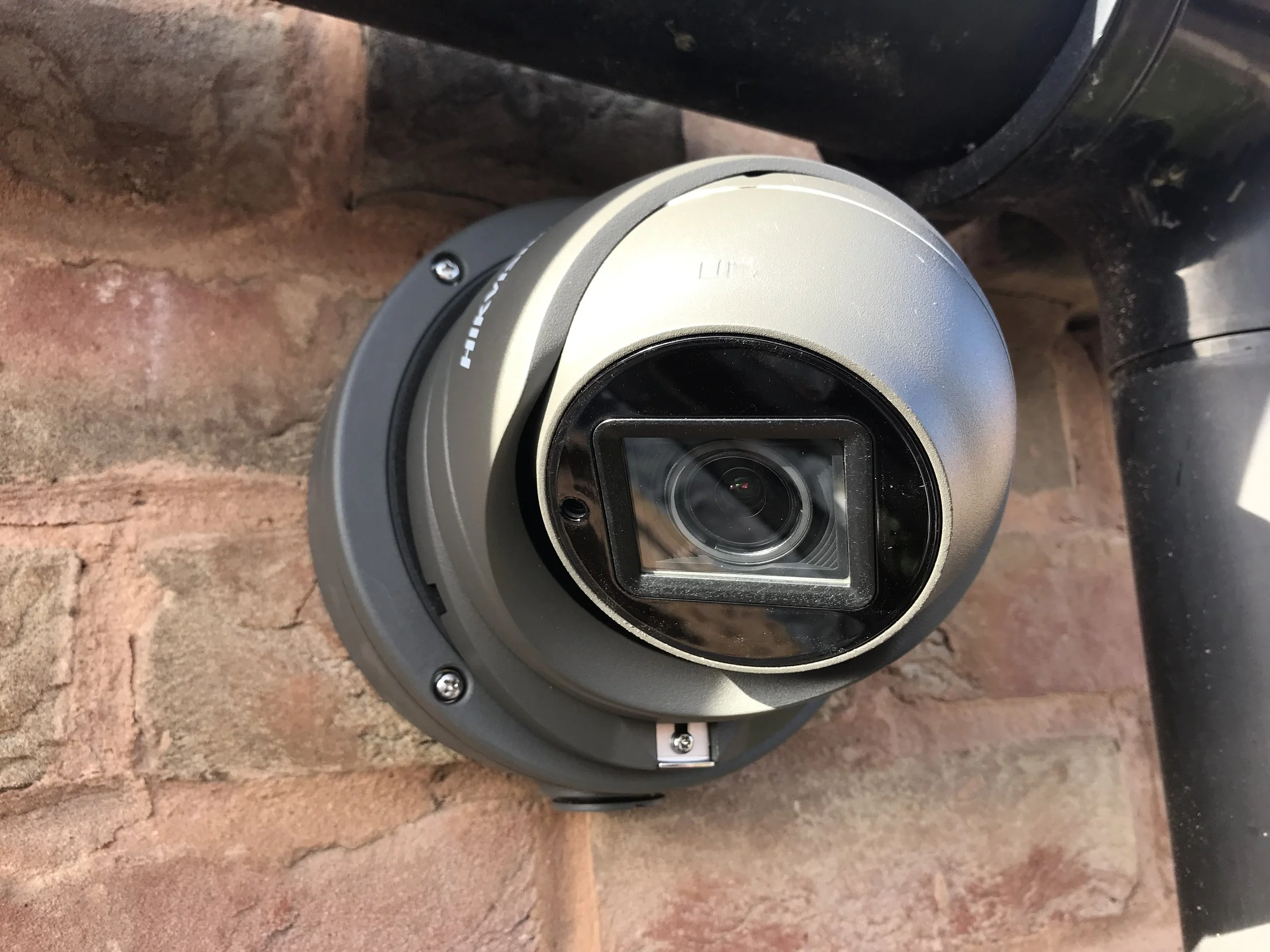 A round security camera mounted on a brick wall.