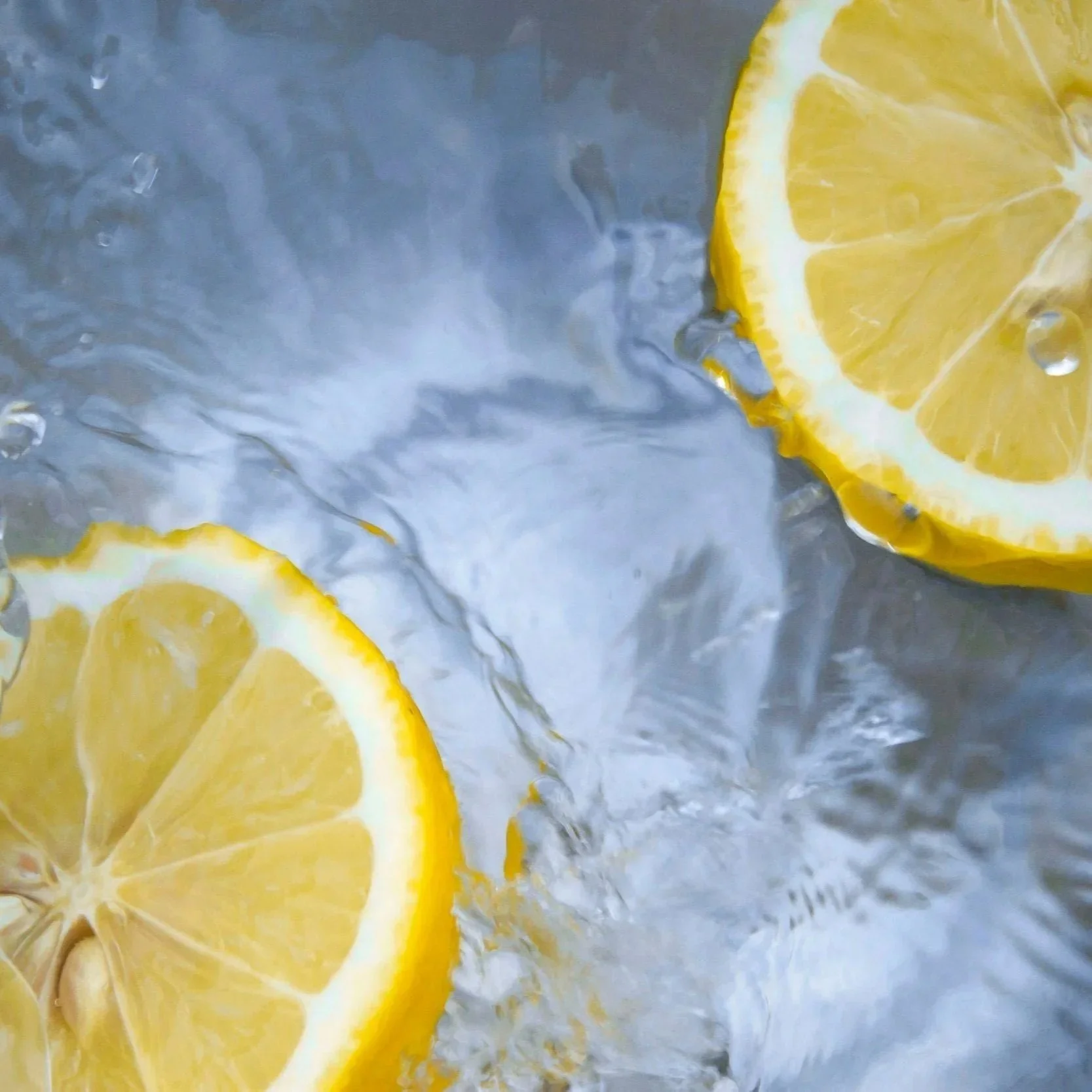 Close-up of lemon slices in water with bubbles and ice.