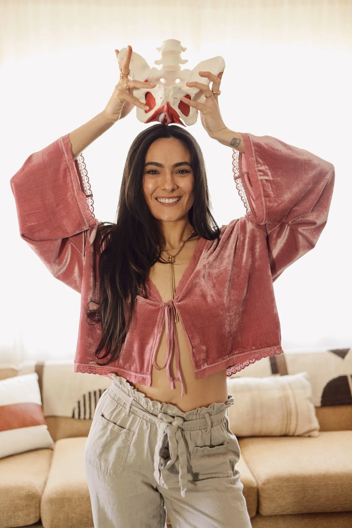 Haley smiling with both hands holding an anatomical pelvis above her head