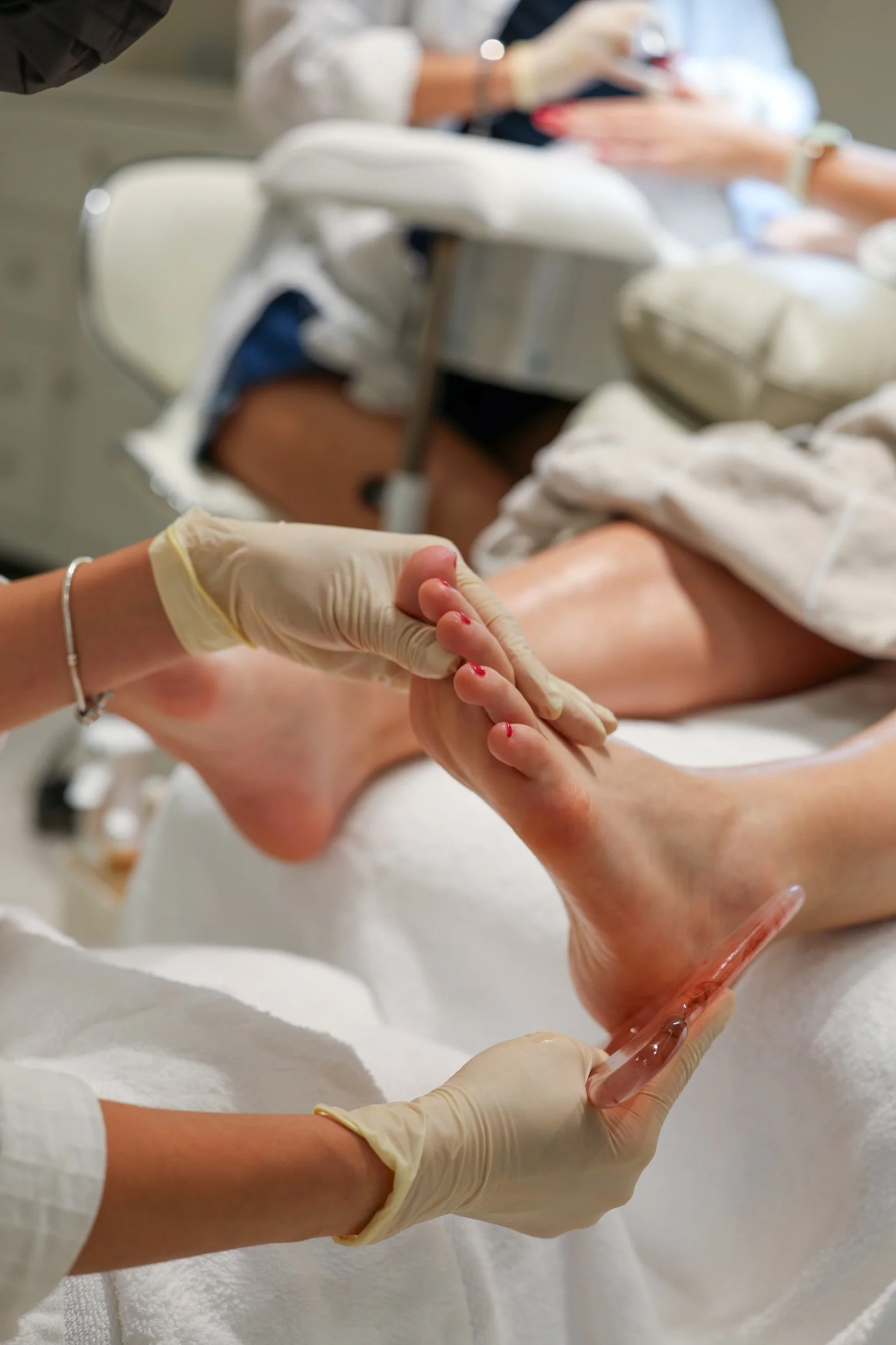 Medical professionals in gloves administering a shot or injection into a patient's arm with a syringe. Blurred background of medical staff and equipment.
