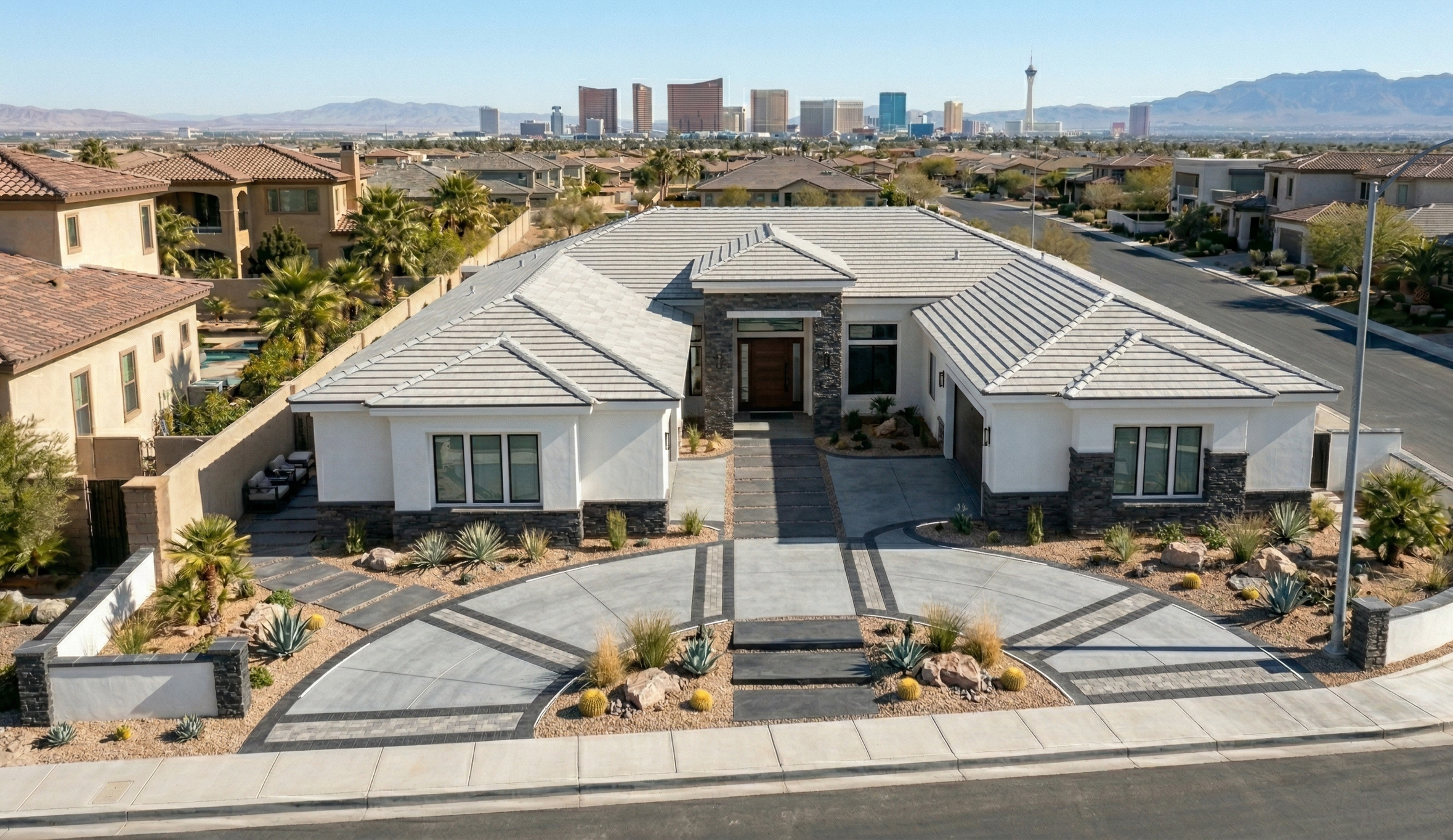 A modern single-story house with a landscaped front yard, featuring desert plants, rocks, and a stone pathway, located in a suburban neighborhood with other houses, and a city skyline with mountains in the background.