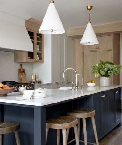 Modern kitchen with navy blue island, white marble countertop, gold accents, and pendant lighting.