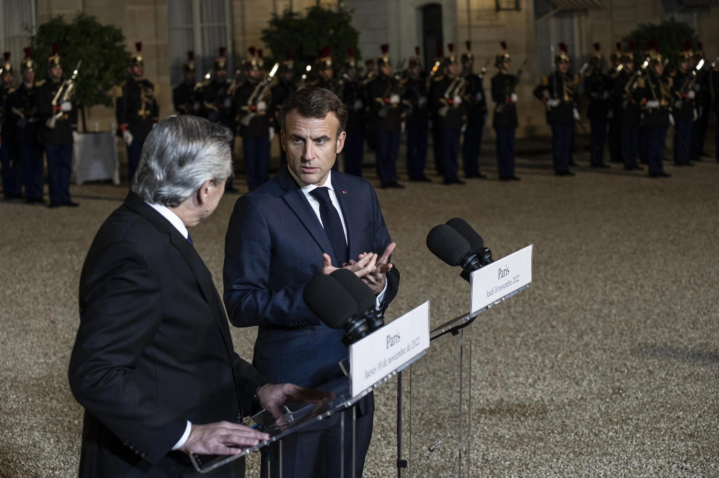 Une réunion officielle avec deux hommes parlant à un micro lors d'une conférence de presse, avec une armée de soldats en uniforme en arrière-plan.