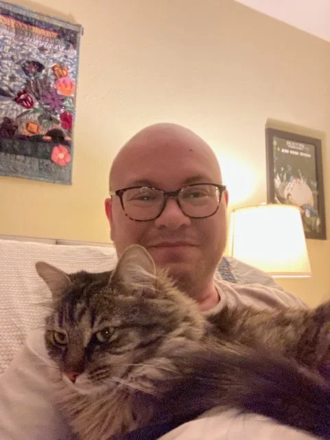 Mo at home, smiling and snuggling with his cat