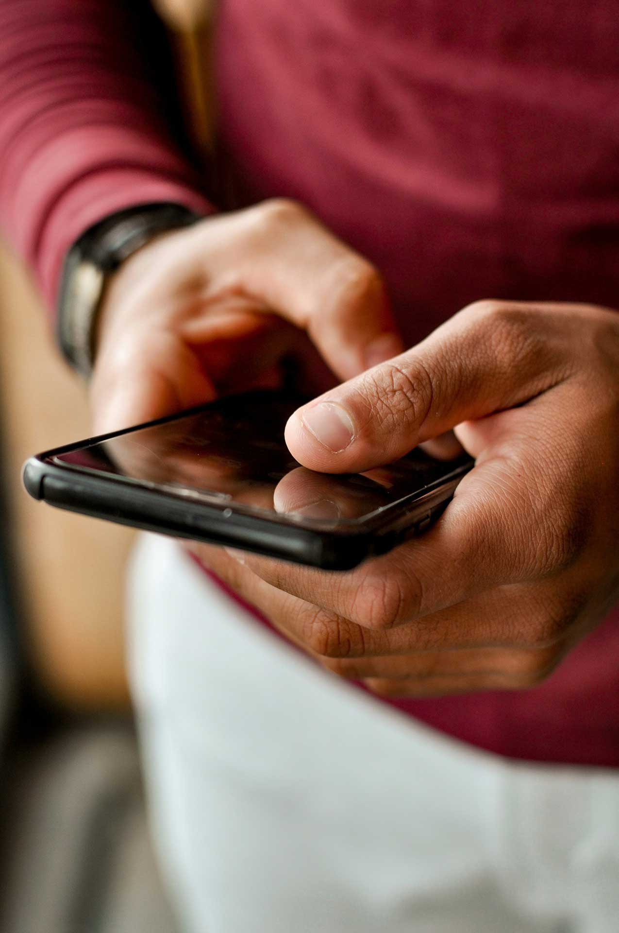Close-up of hands using a smartphone, typing and navigating on the screen