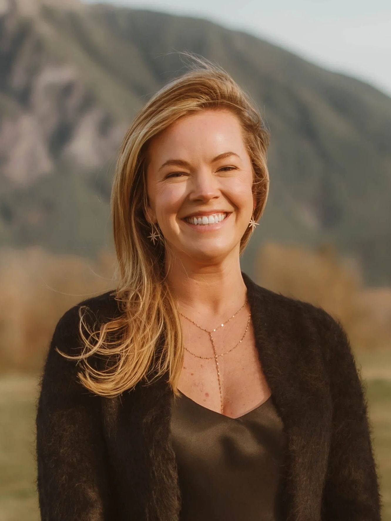 Lacey, one of the cofounders of Hire Collective, smiles at the camera with a mountain background