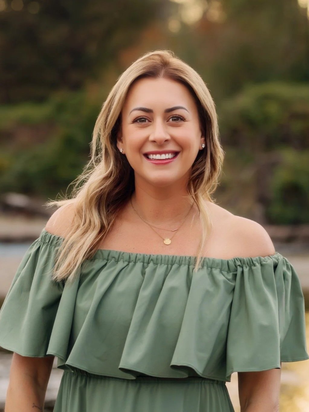 Anne, one of the cofounders of Hire Collective, smiles at the camera with a forest background