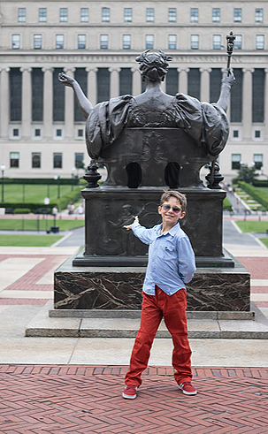 Child posing in front of the alma mater of Columbia University.