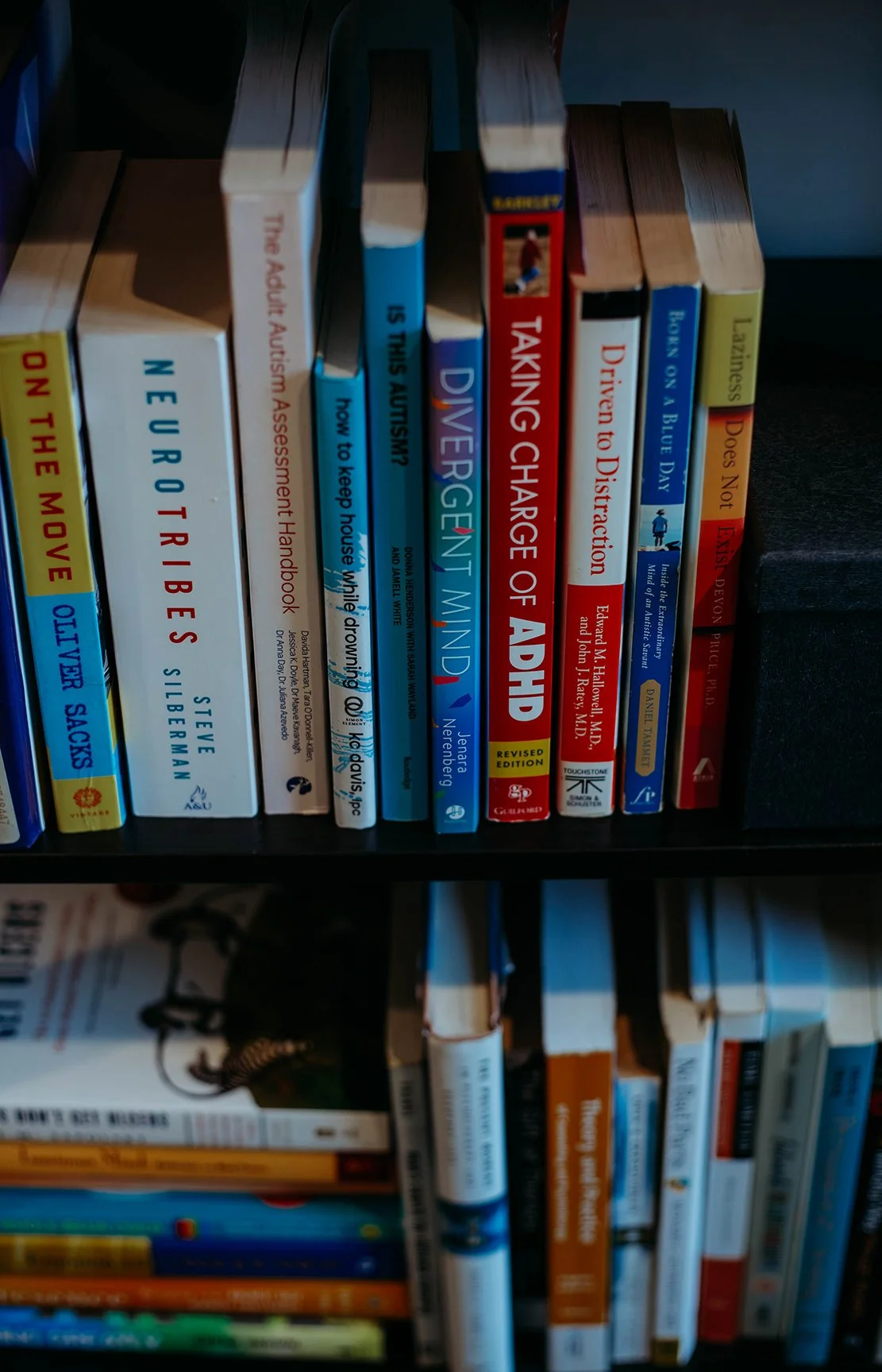 Books on a bookshelf including titles like "On The Move," "Neurosis," "Is This Autism?" and "Divergent Mind."