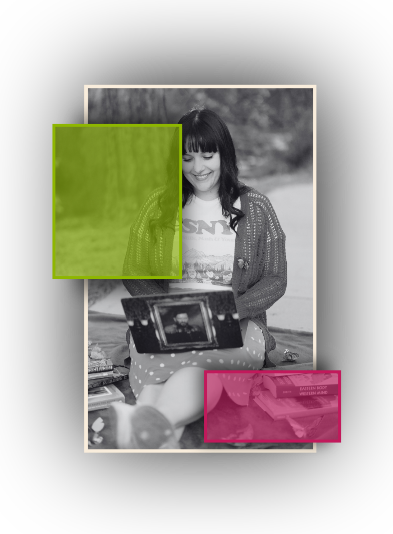 A woman with dark hair and bangs, smiling while sitting outdoors, looking at a framed photograph on her lap. She is wearing a T-shirt with a mountain scene and a knitted sweater. Books are stacked beside her, with one titled 'Eastern Body Western Mind'. The photo has two overlaid colored boxes: a green box partially covering her face and close-up of her upper body, and a pink box over the books.
