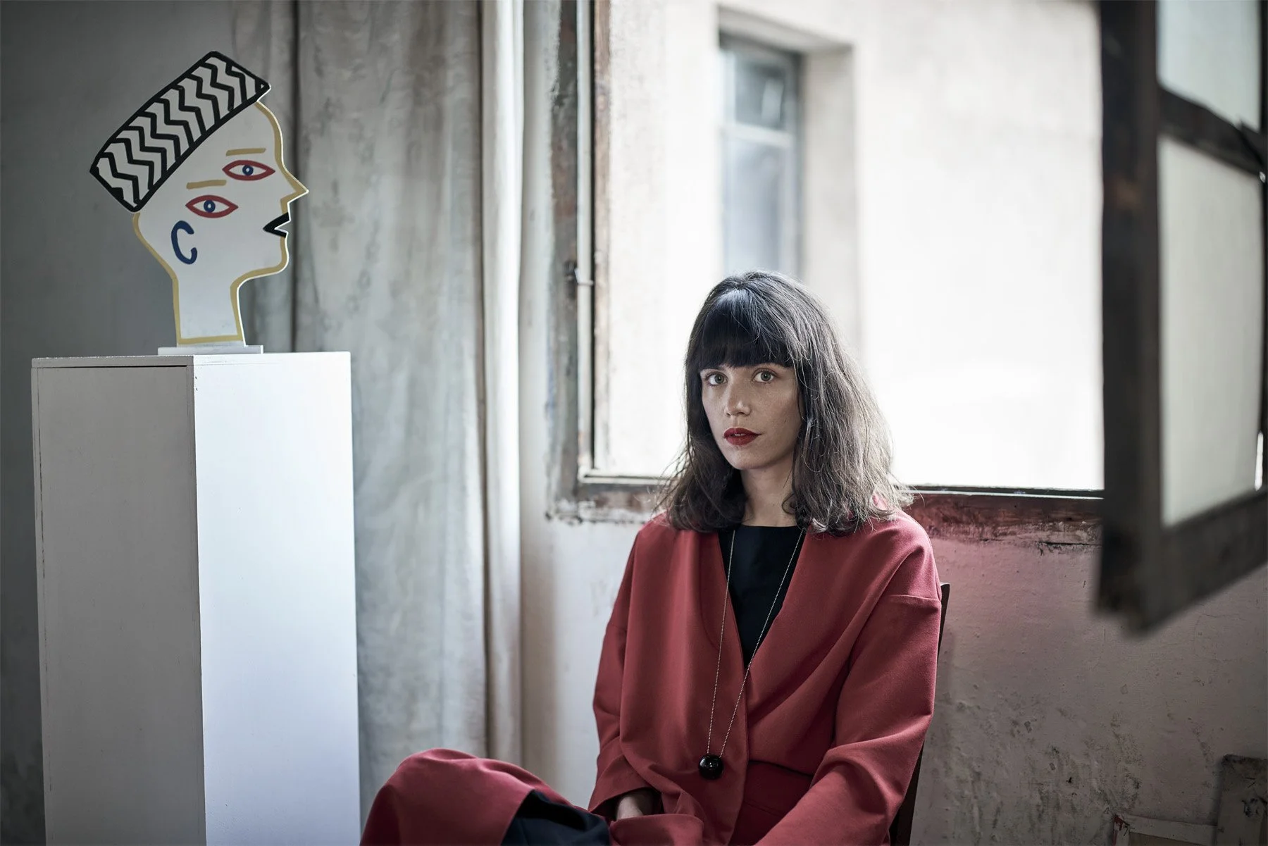 artist blanca miro sitting next to a sculpture of a head